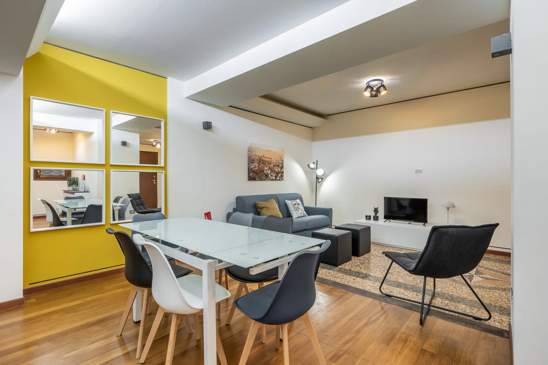Sala de estar y comedor con una mesa de vidrio y asientos frente a un televisor.