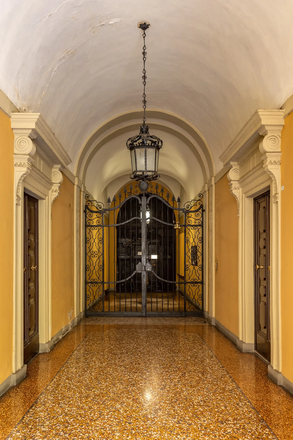 Un pasillo interior ornamentado con techo abovedado y una reja decorativa de hierro.