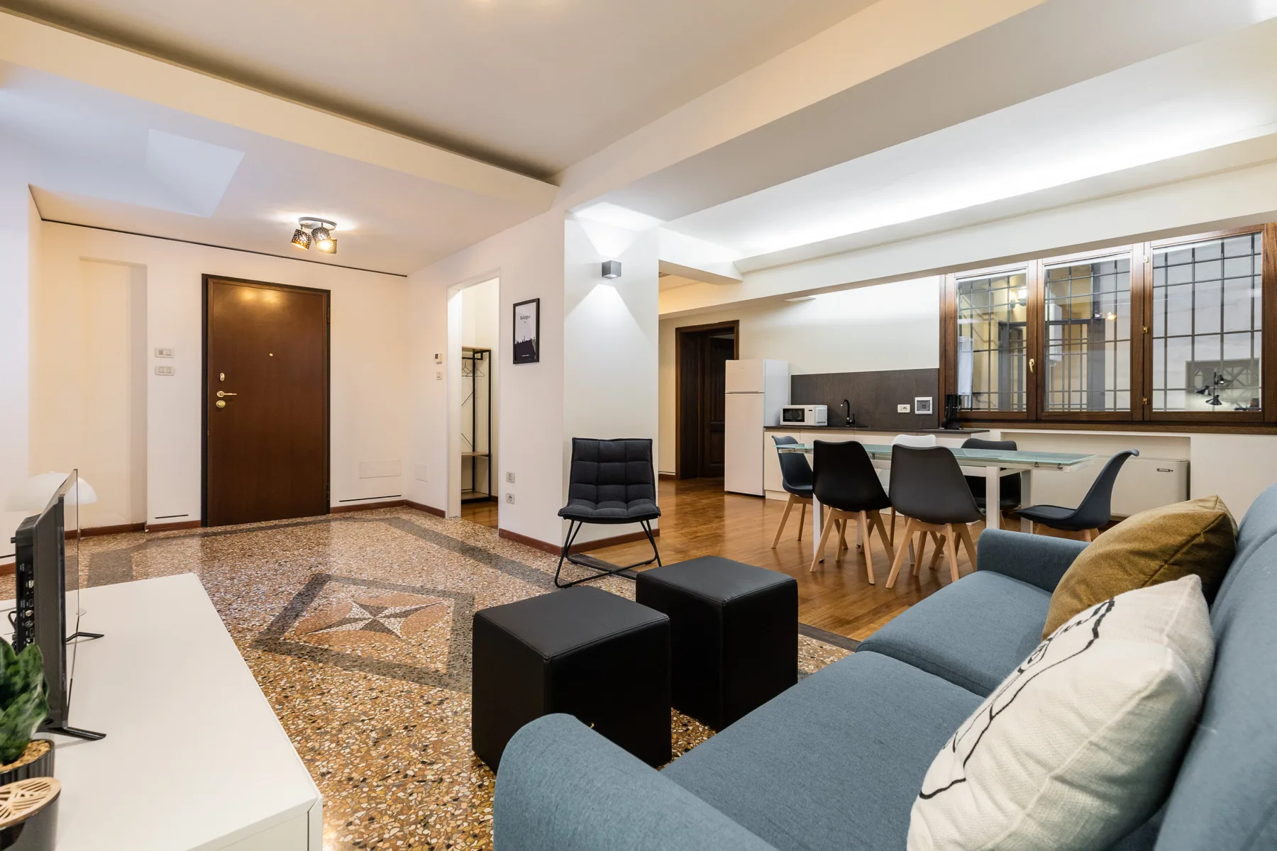Una sala-comedor de concepto abierto cuenta con un sofá, una mesa de comedor y una puerta oscura.