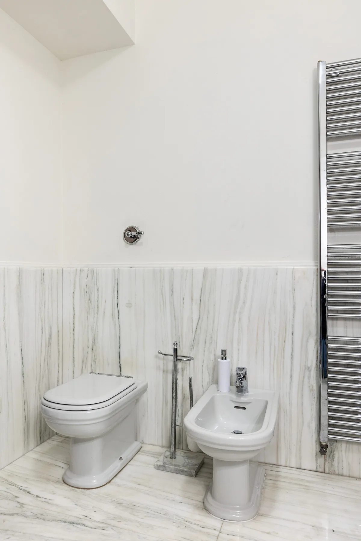 Un baño revestido de azulejos con un inodoro suspendido y un bidé.