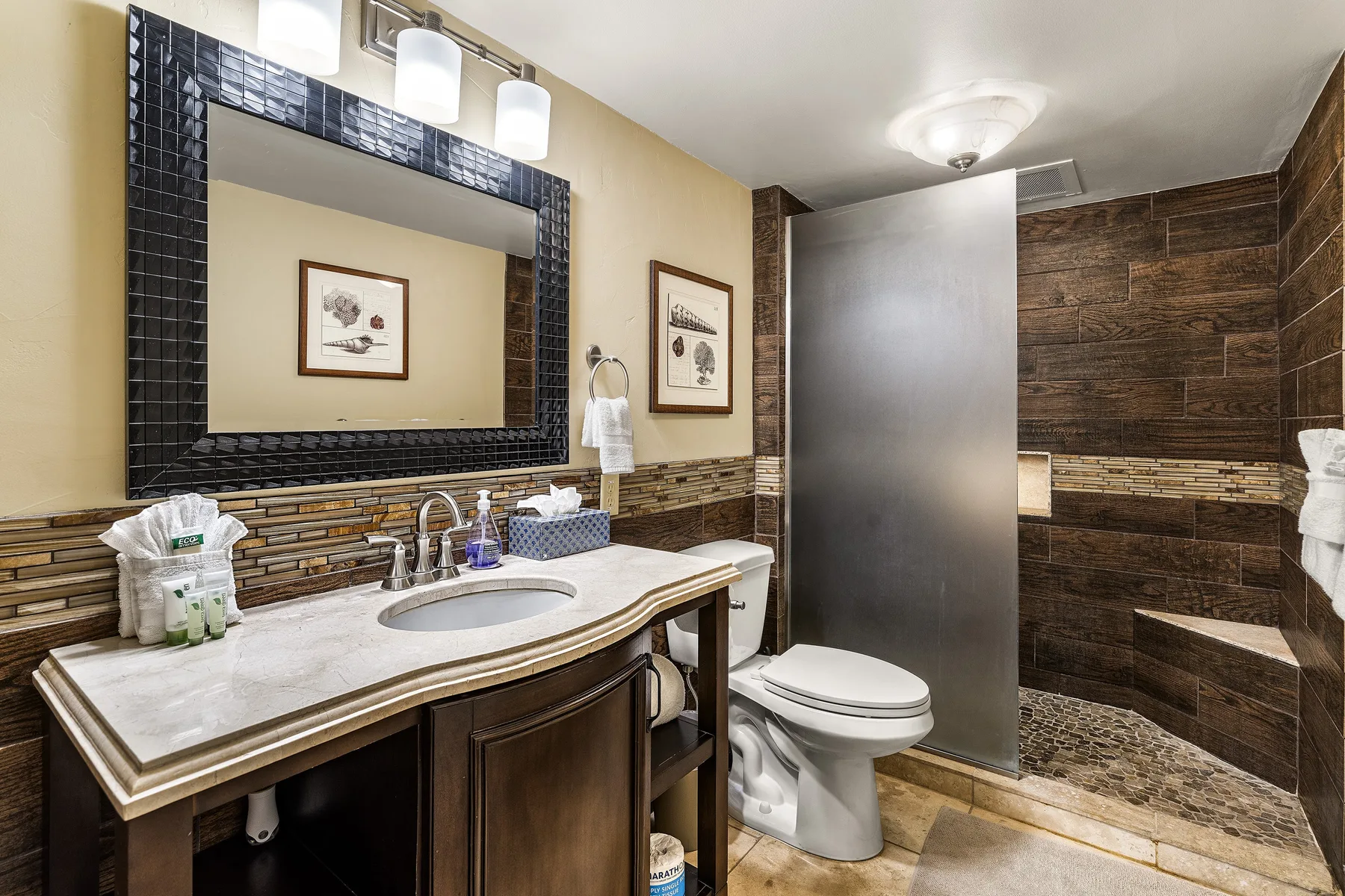 Un baño con un tocador largo, espejo de pared, inodoro y zona de ducha.