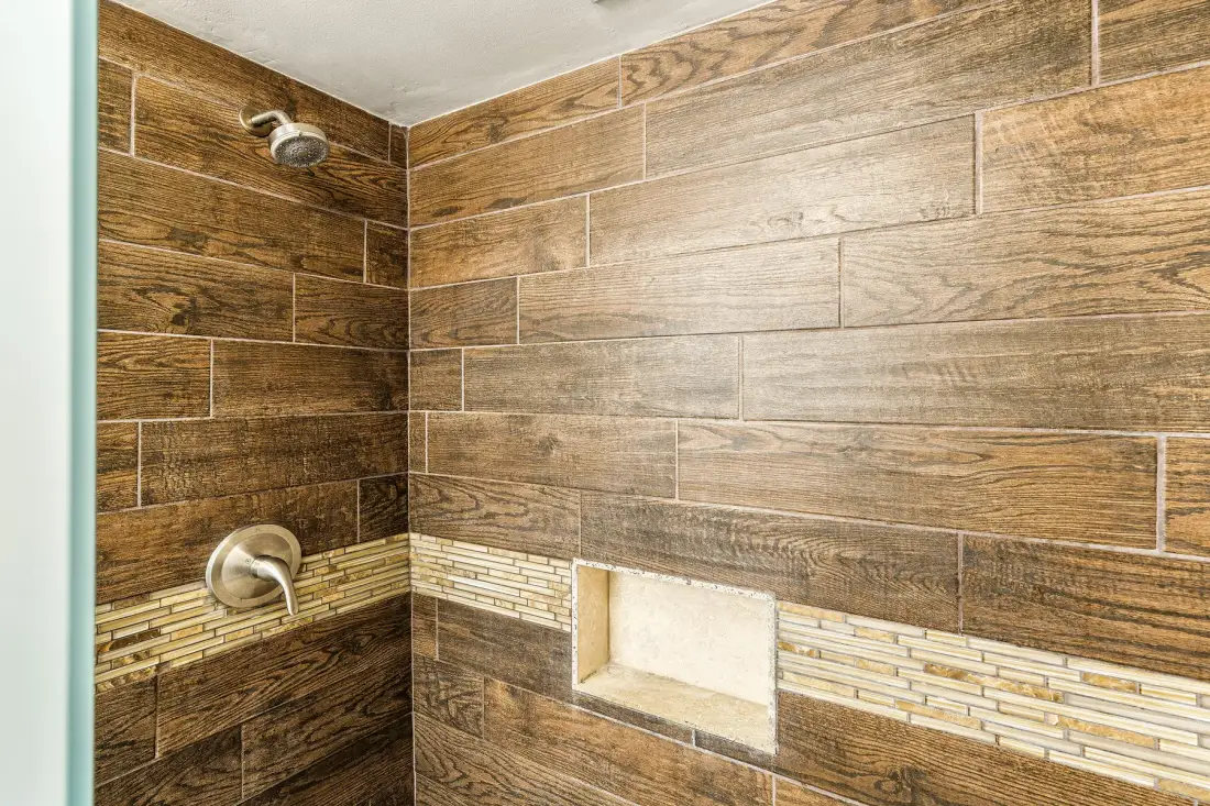Una ducha de azulejos con un nicho empotrado y grifería metálica.