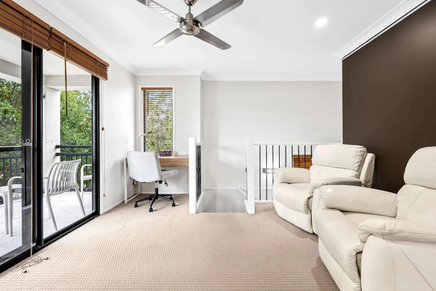 A bright seating area with recliners beside a small desk and sliding glass doors.