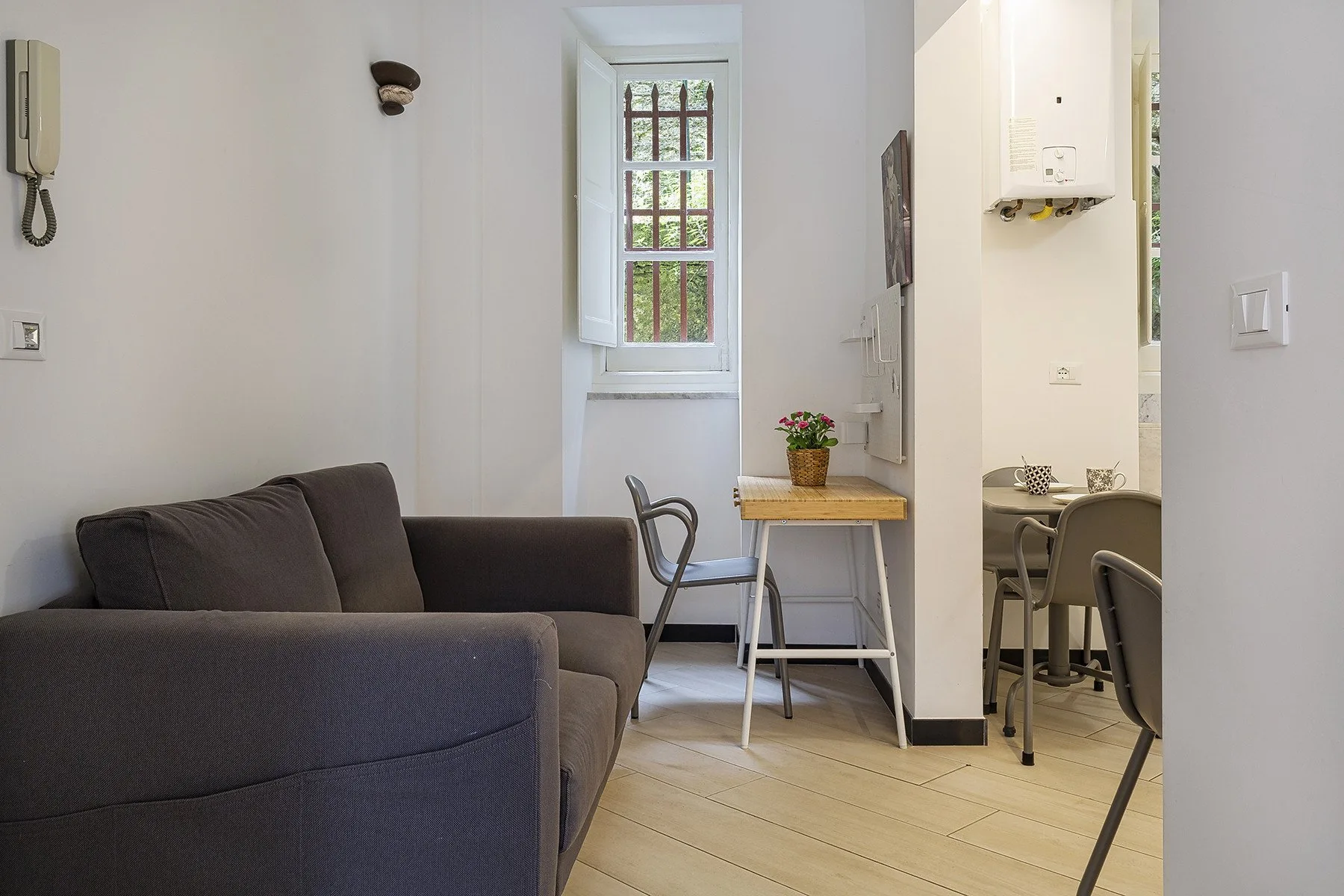 A living area with dark seating and a small table beside a window.
