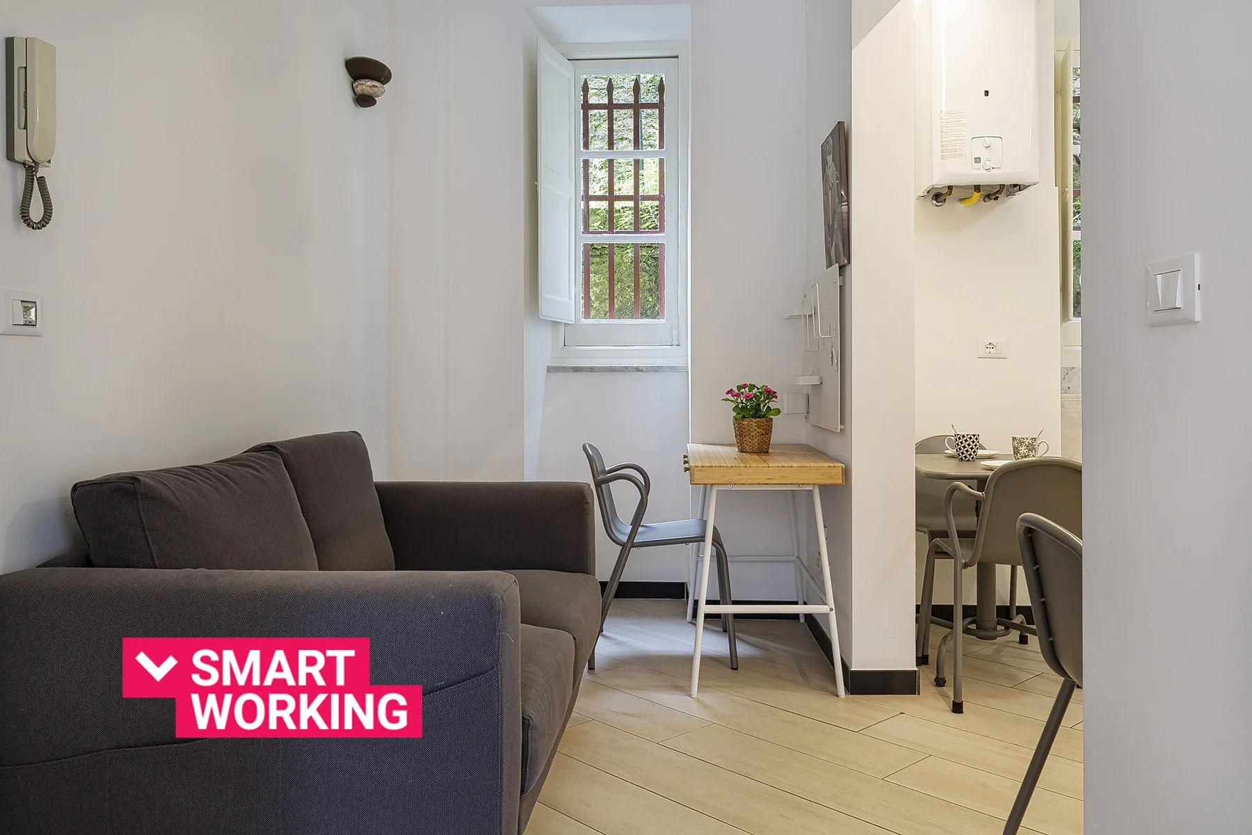 A compact living area with dark seating beside a window and small table.
