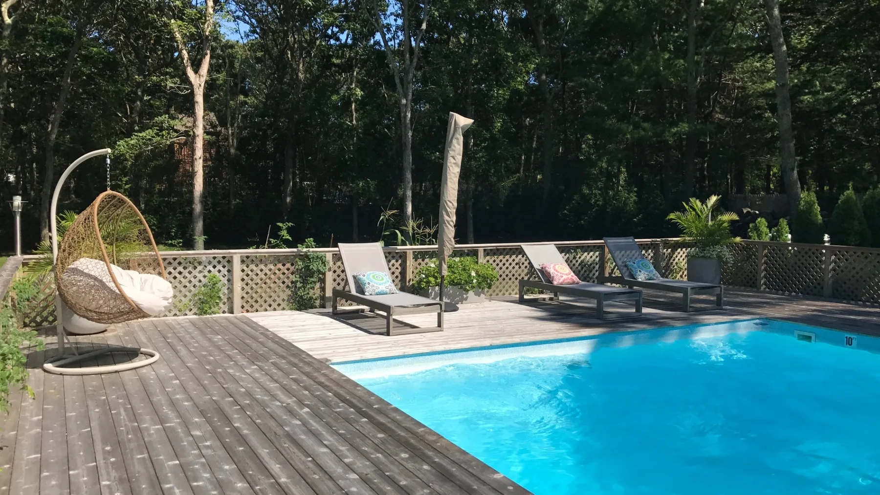 Una piscina al aire libre junto a una terraza de madera con asientos.