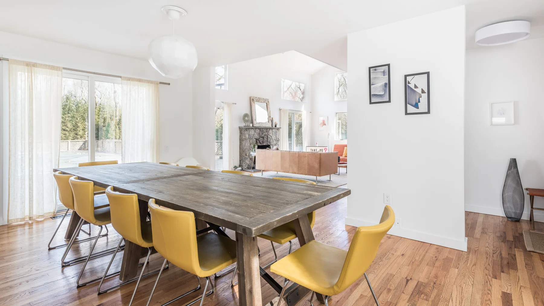 A bright dining area with a long wooden table and yellow seating.