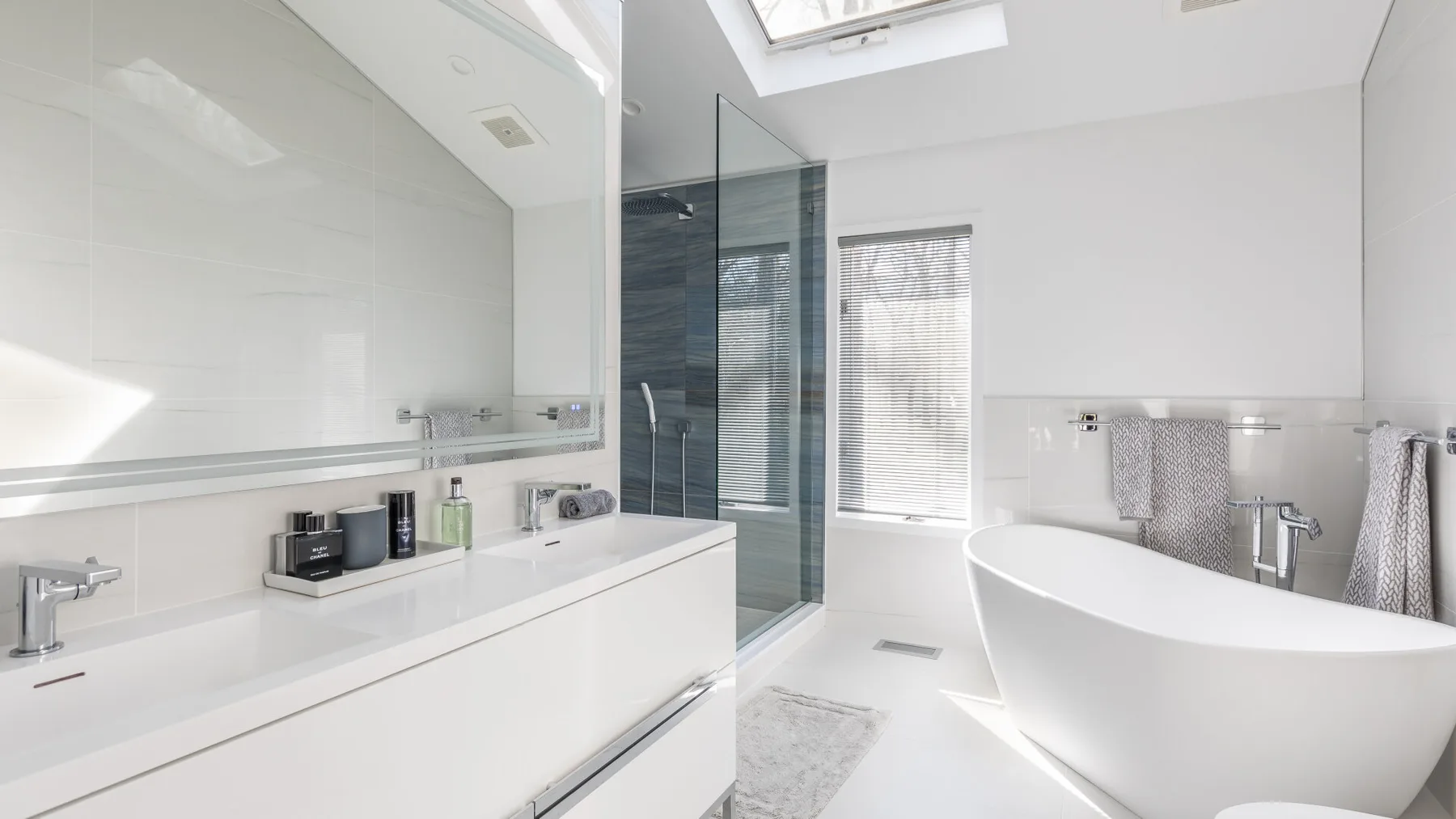 Un baño luminoso cuenta con una bañera exenta y una ducha con paneles de vidrio.