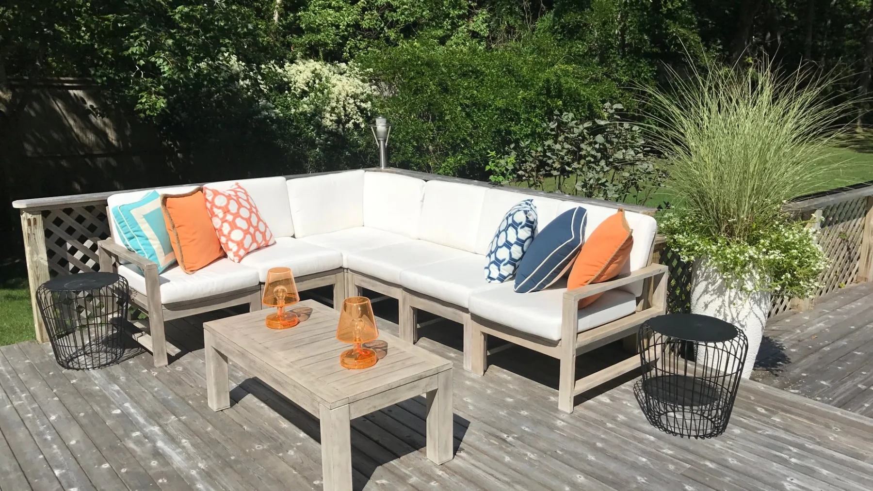 Una zona de estar al aire libre cuenta con un sofá seccional claro y una mesa baja de madera.