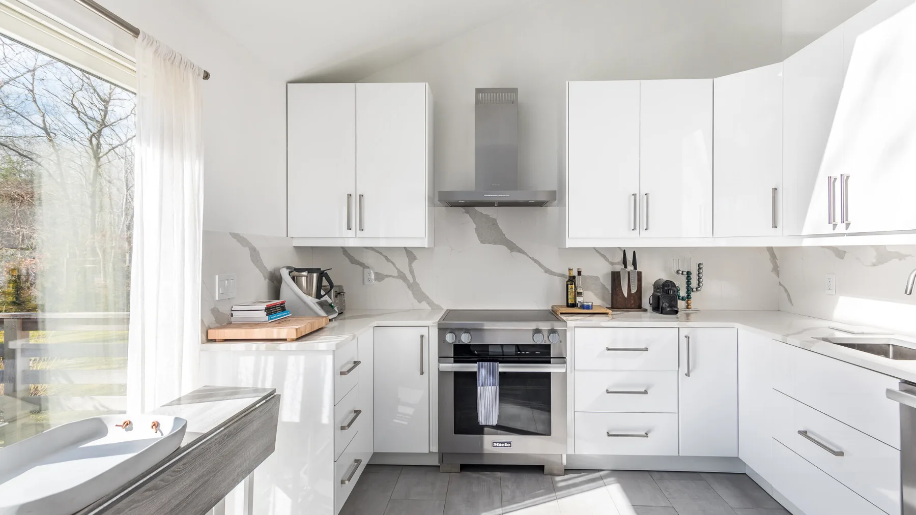 Una cocina luminosa con armarios blancos y un horno empotrado.