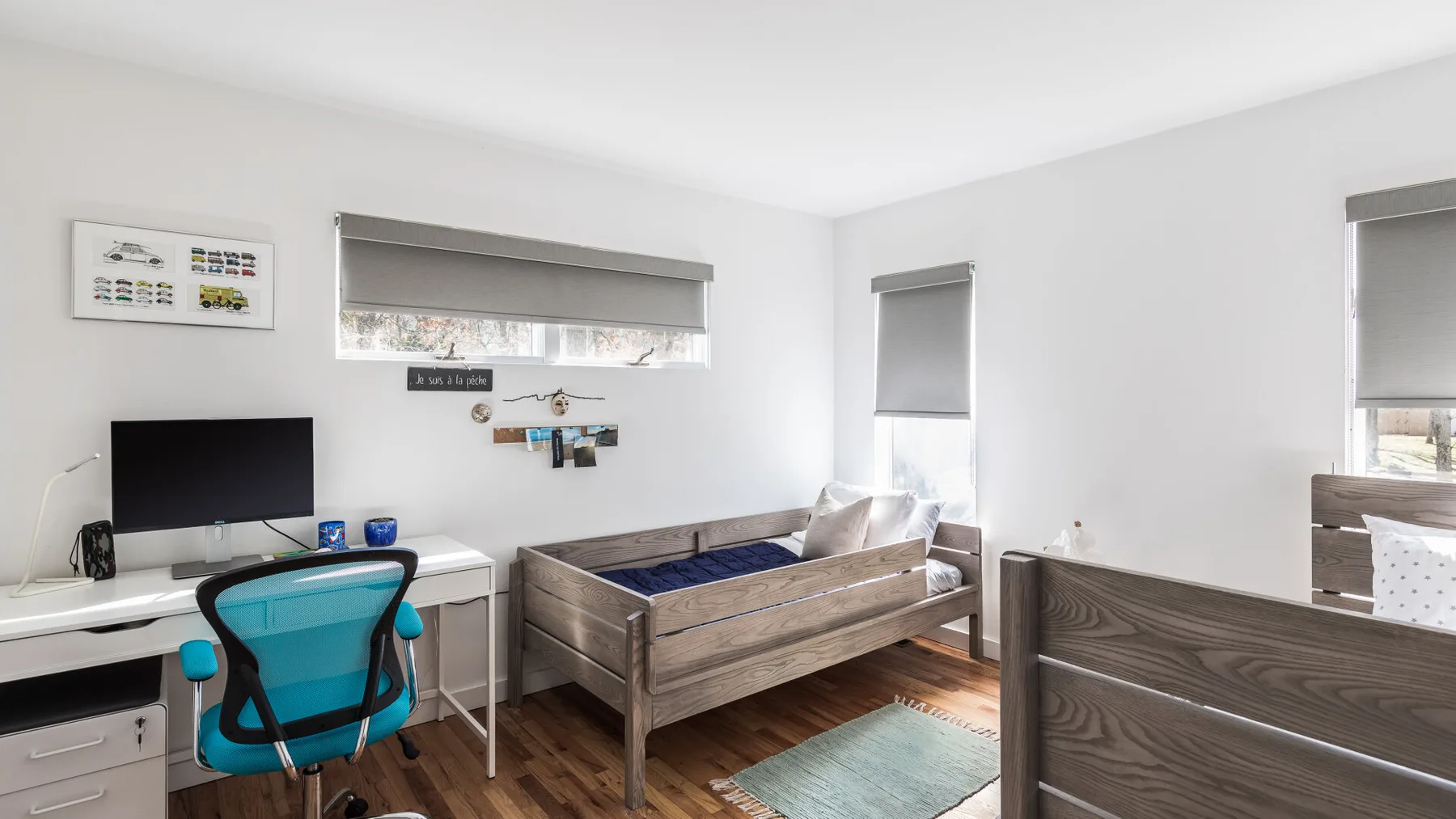 Un dormitorio luminoso con una cama, un escritorio y una silla azul.