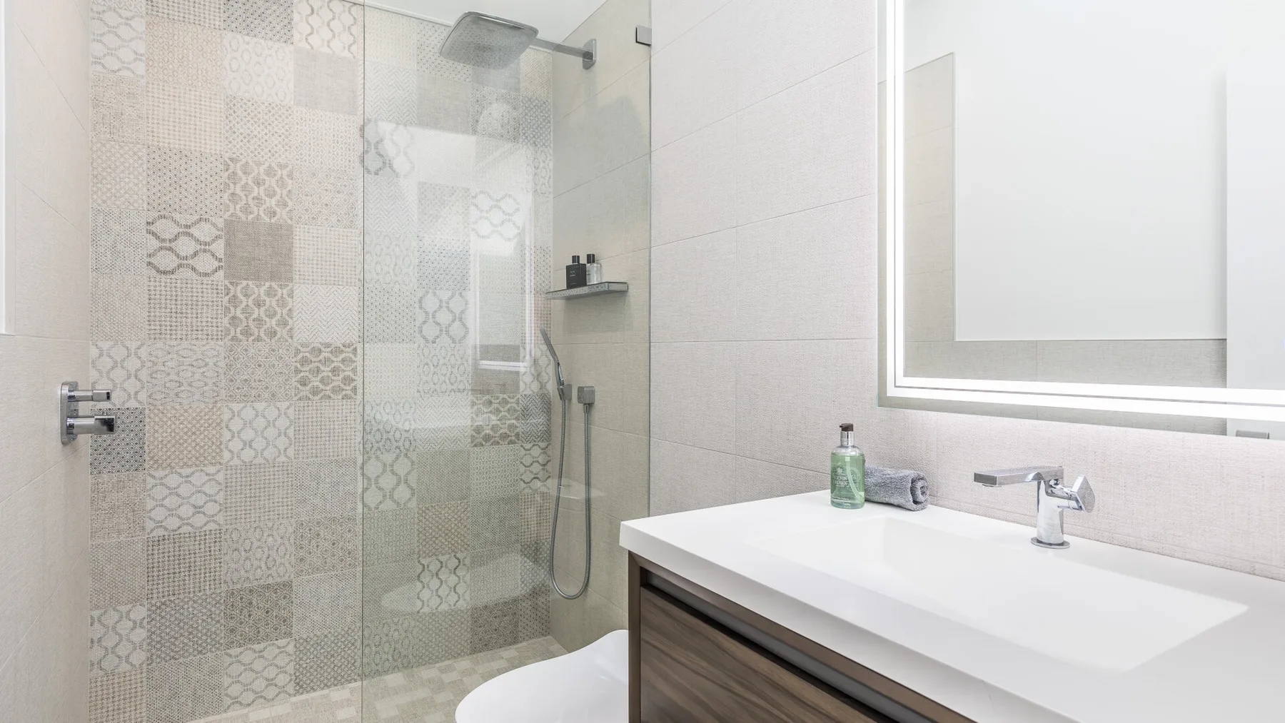 Un baño luminoso con una ducha de vidrio y un lavabo blanco.