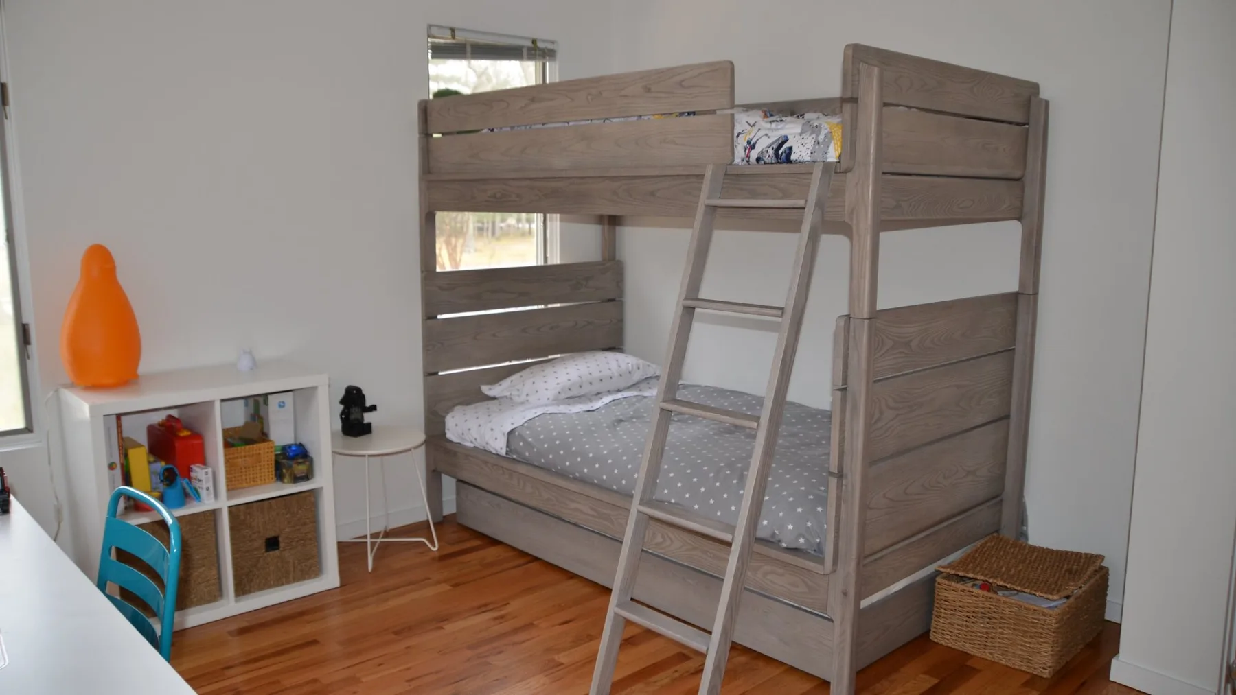 Un dormitorio con una litera de madera, una escalera y un pequeño mueble de almacenaje.