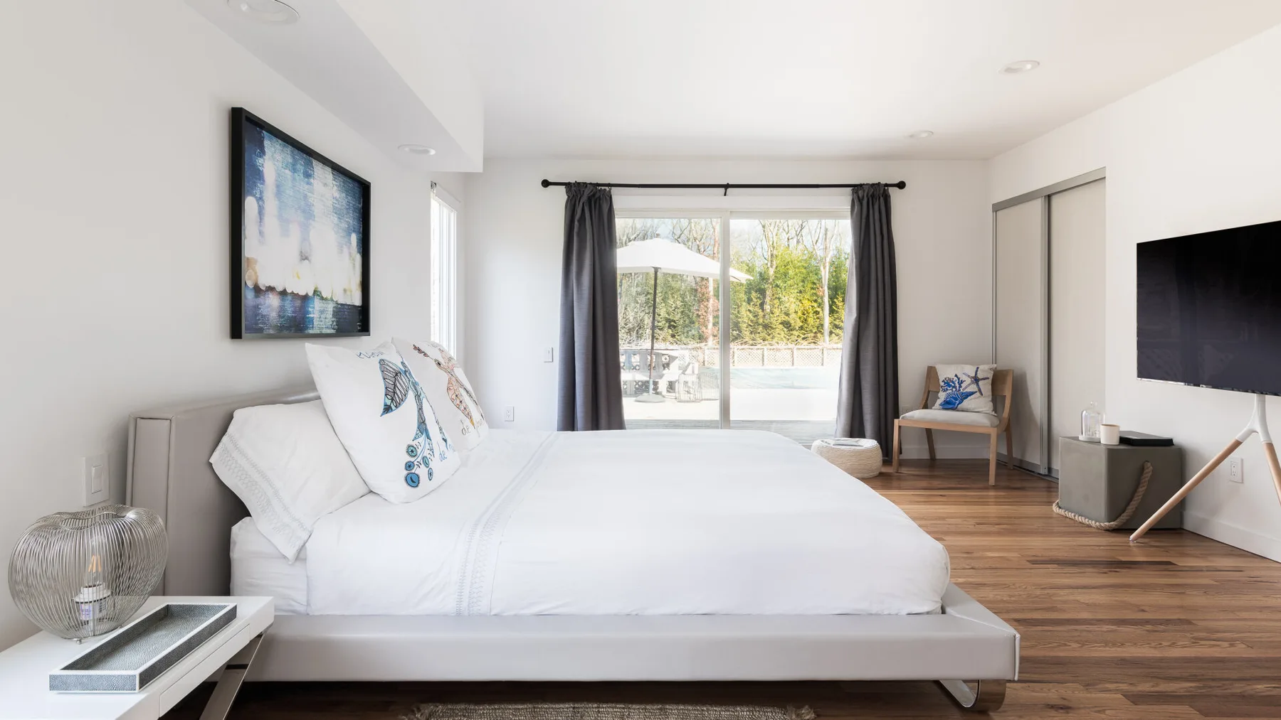 Un dormitorio luminoso con una cama grande y puertas corredizas de vidrio que dan a un patio.