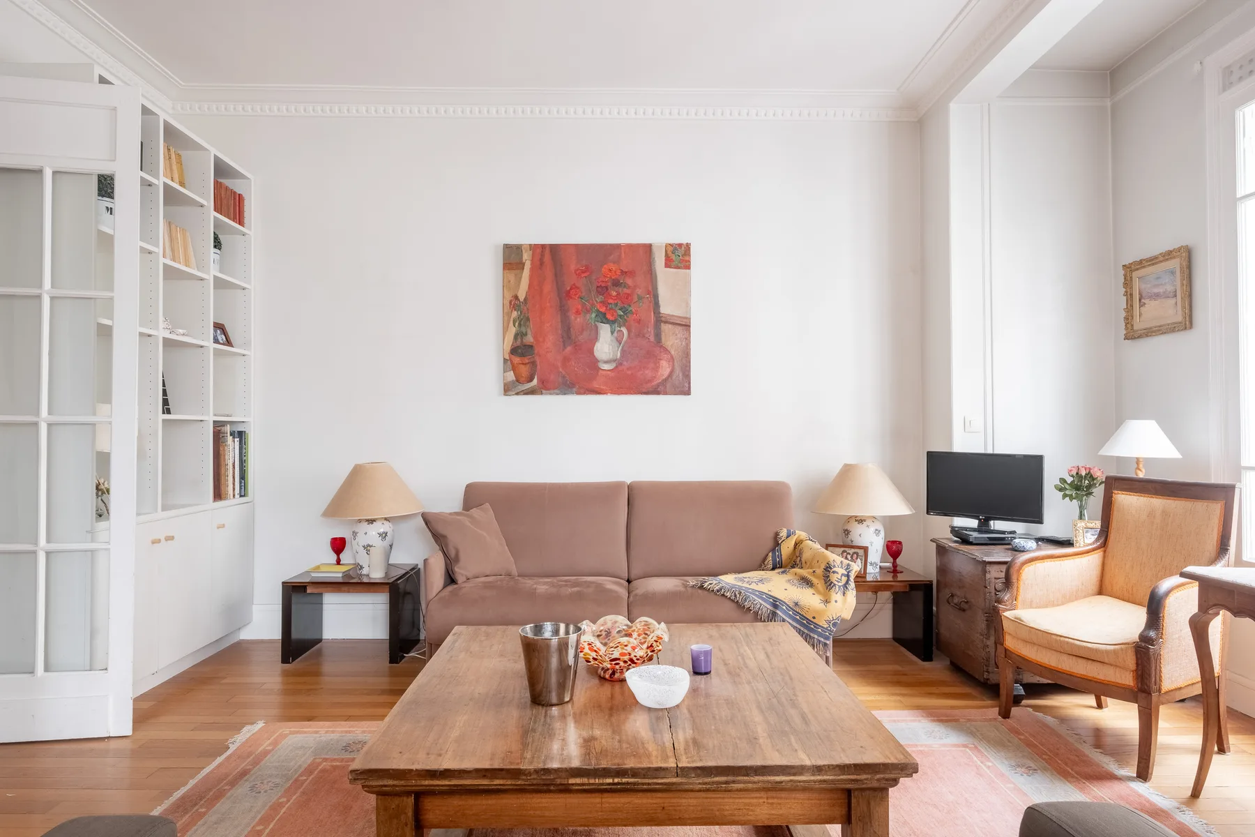 Una sala de estar luminosa con asientos, una mesa de centro de madera y estanterías empotradas.