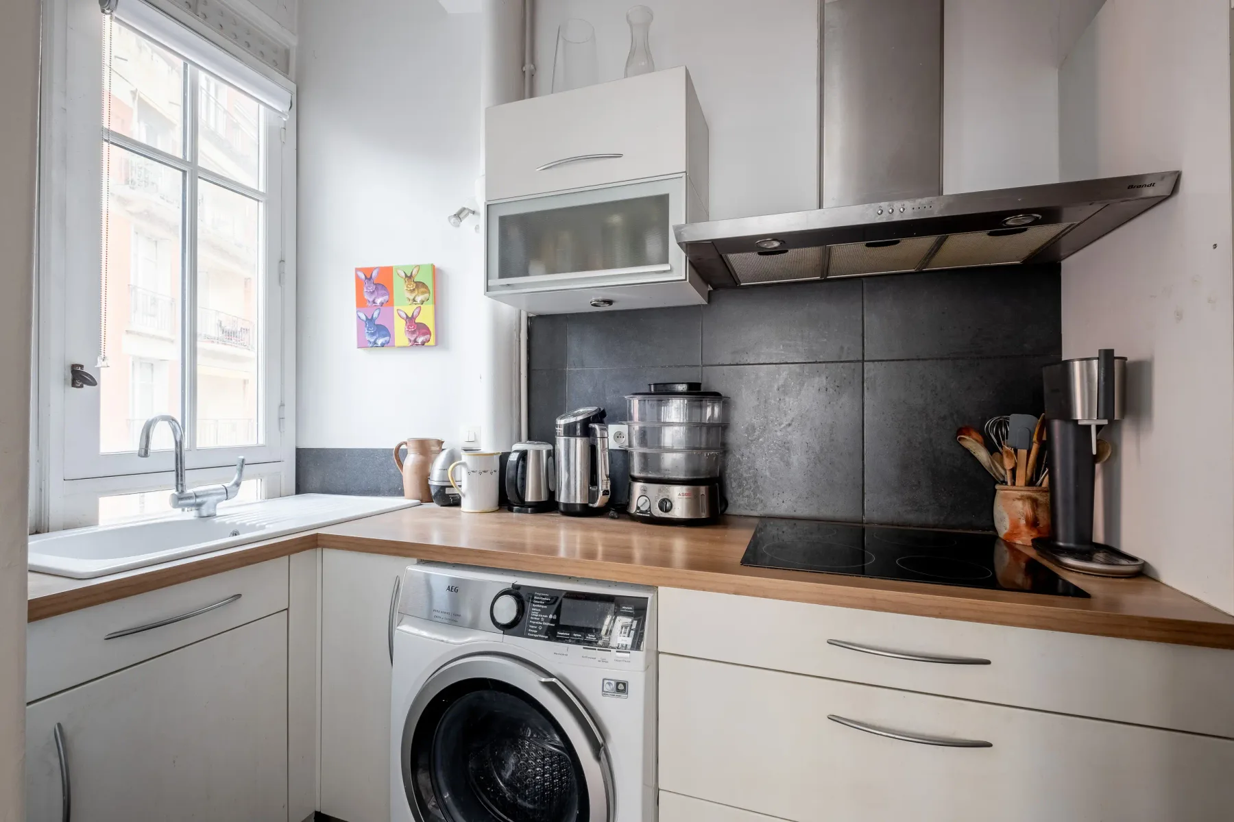 Una cocina luminosa con una ventana, una encimera de madera y electrodomésticos.