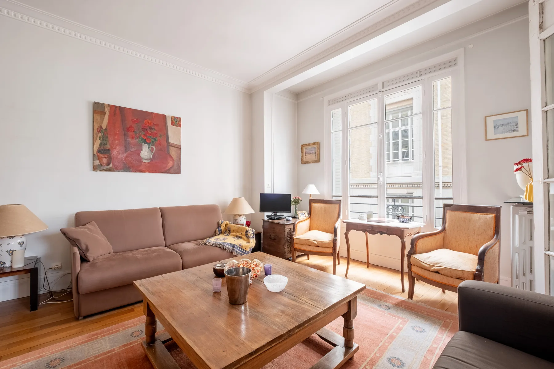 Una sala luminosa con asientos, una mesa de centro de madera y ventanas altas.