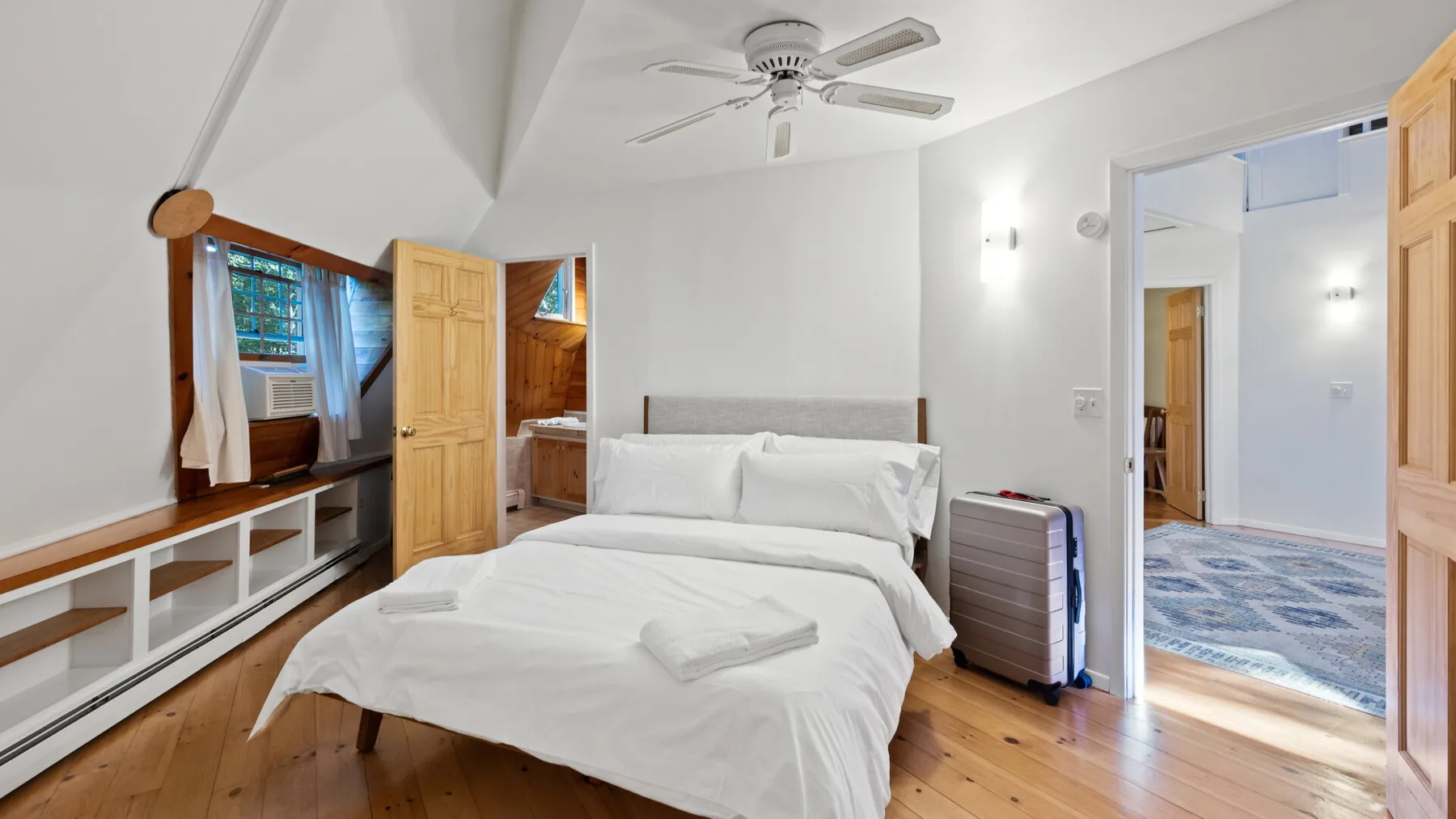 Dormitorio con una cama, suelo de madera y una puerta abierta.