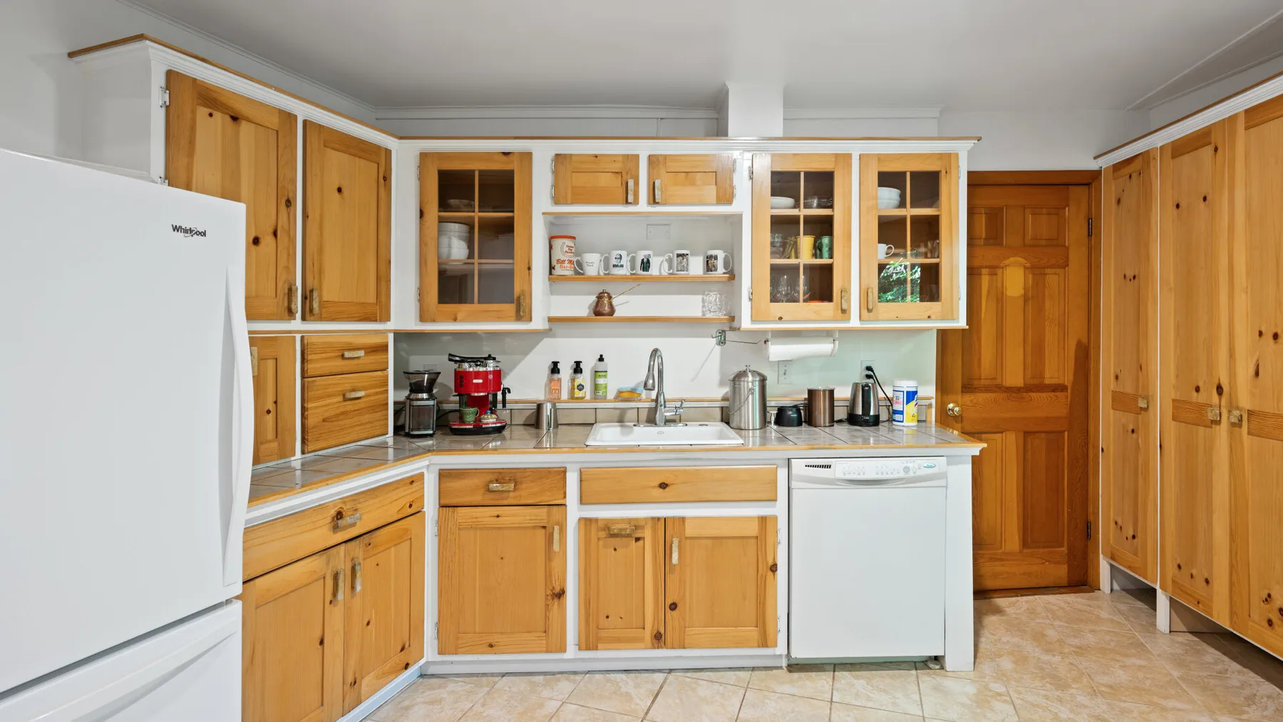 Una cocina con gabinetes de madera, un refrigerador y un fregadero.