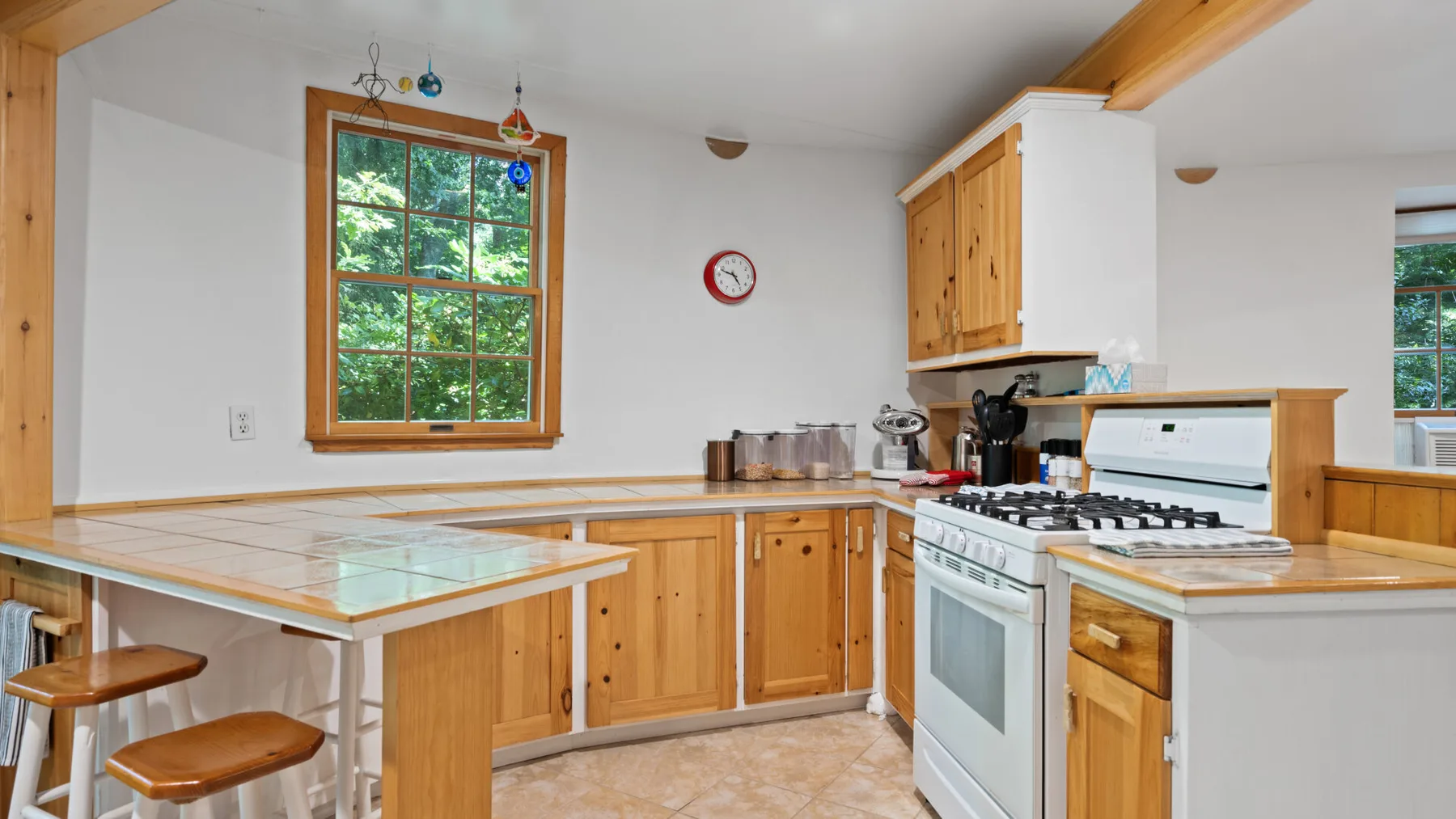 Una cocina luminosa con gabinetes de madera, una encimera de azulejos y una estufa blanca.