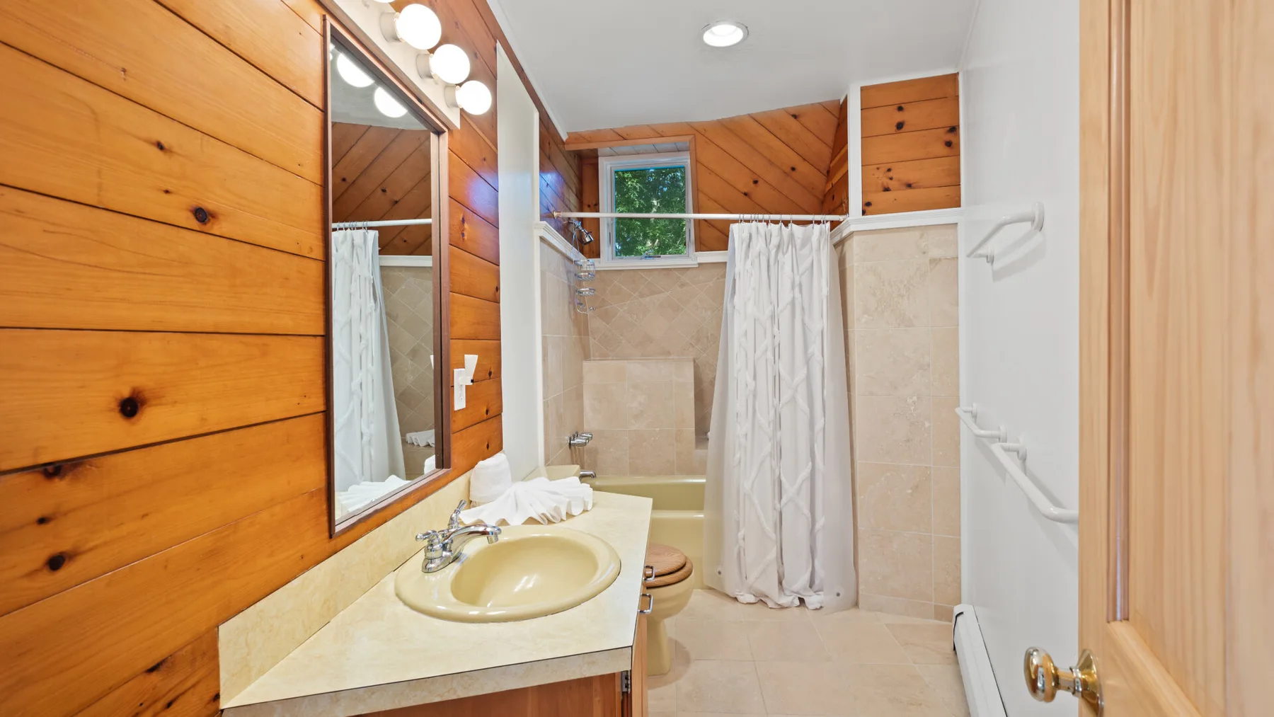 Un baño con lavabo, espejo y ducha con cortina.