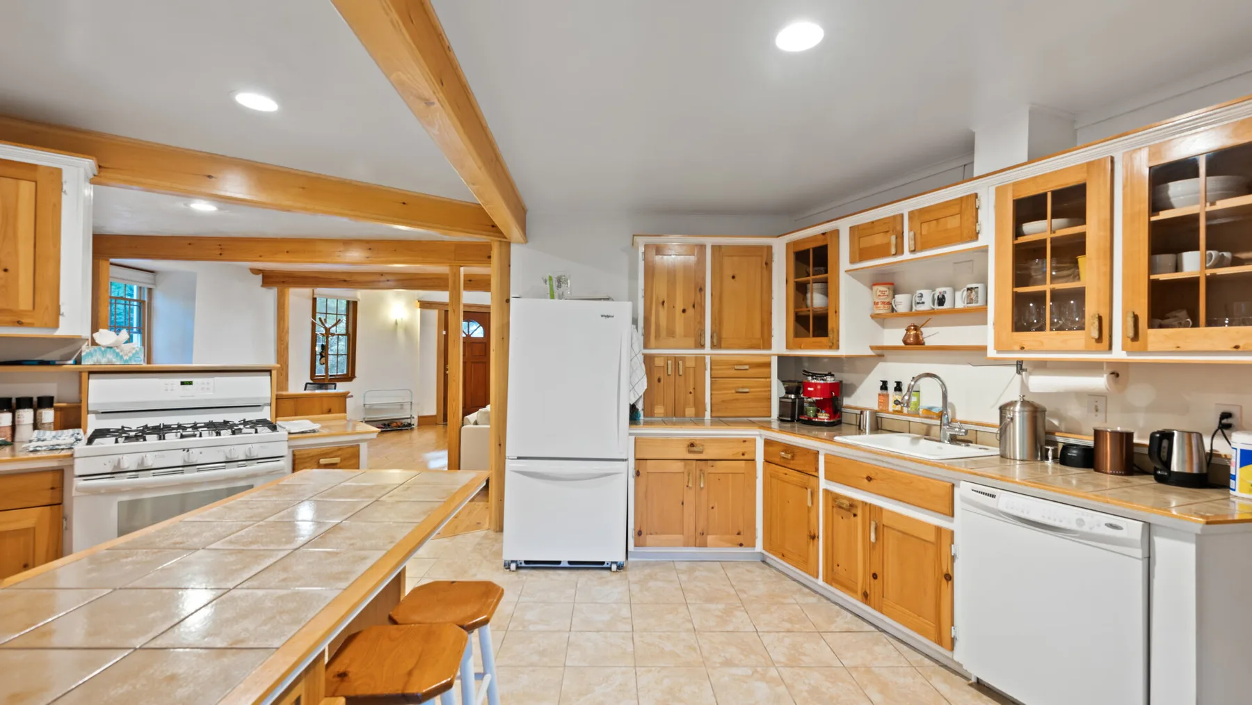 Una cocina luminosa con gabinetes de madera, un refrigerador y una encimera de azulejos.