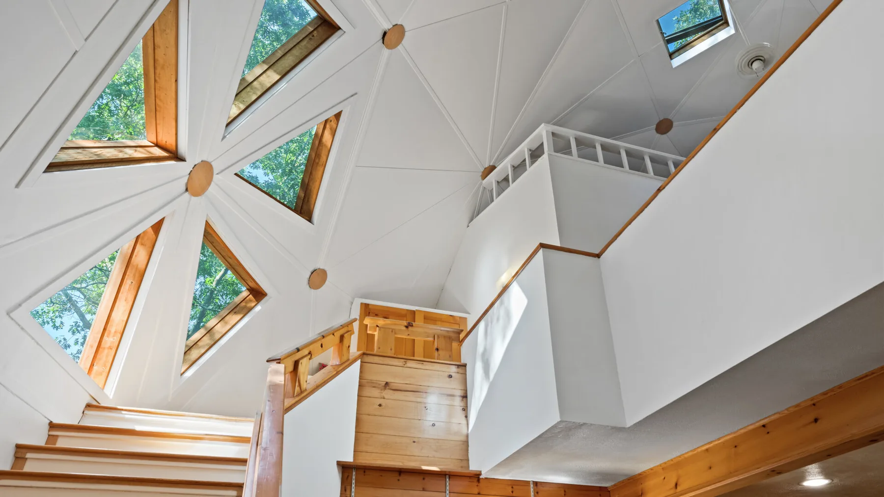 Un interior de loft luminoso con una escalera de madera y tragaluces.
