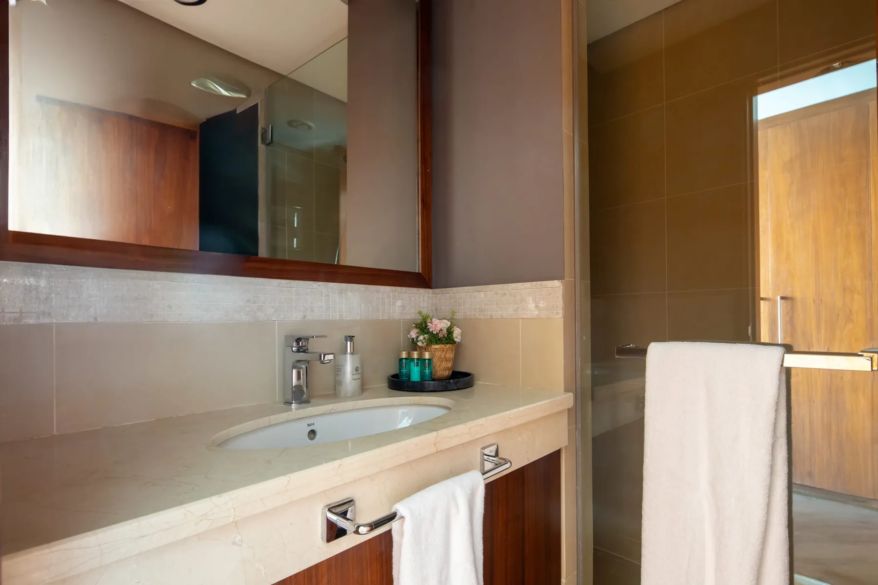 A bathroom vanity with a wide mirror and a glass shower.