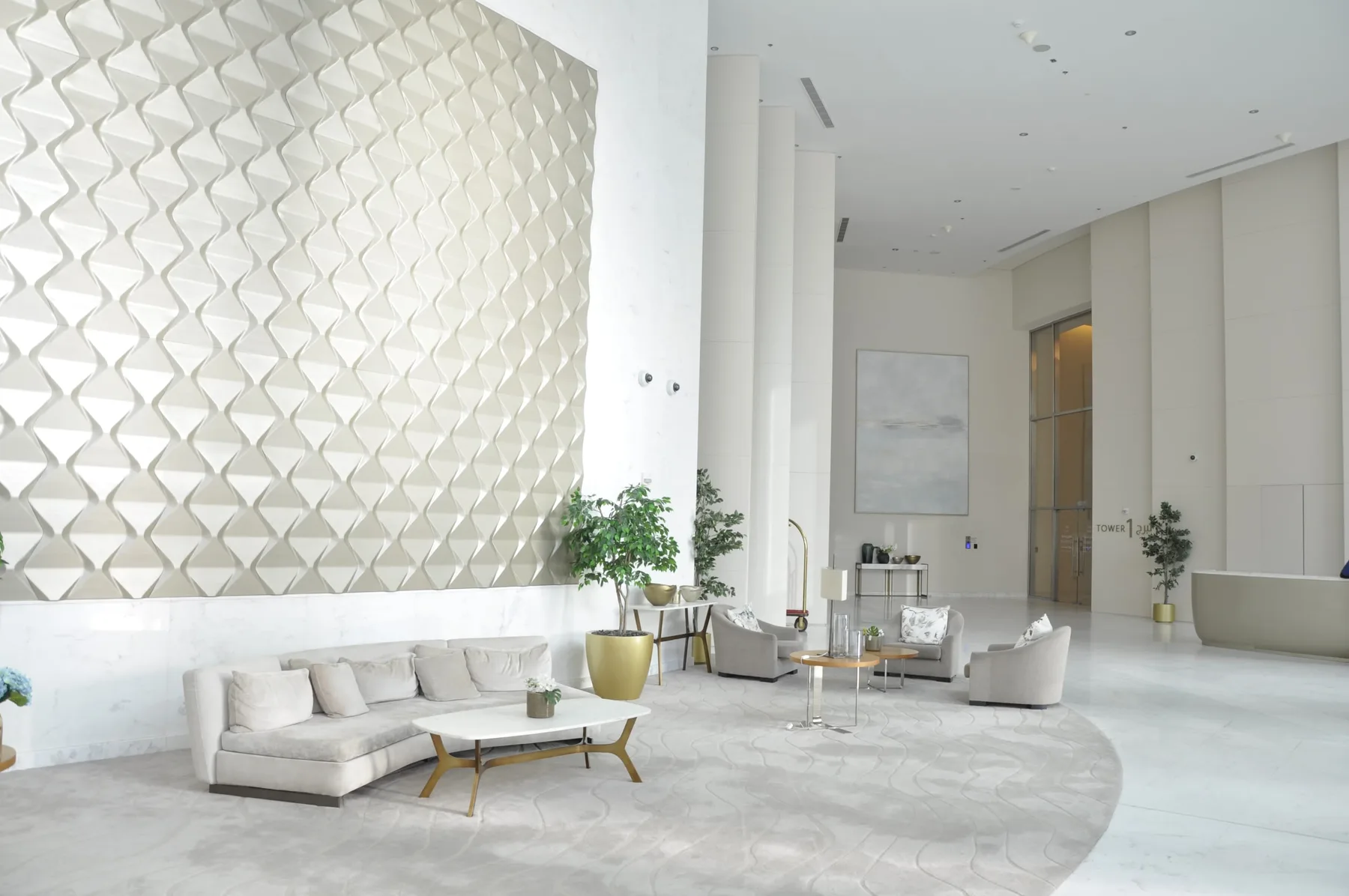 A bright modern lounge with pale seating and a sculpted wall feature.