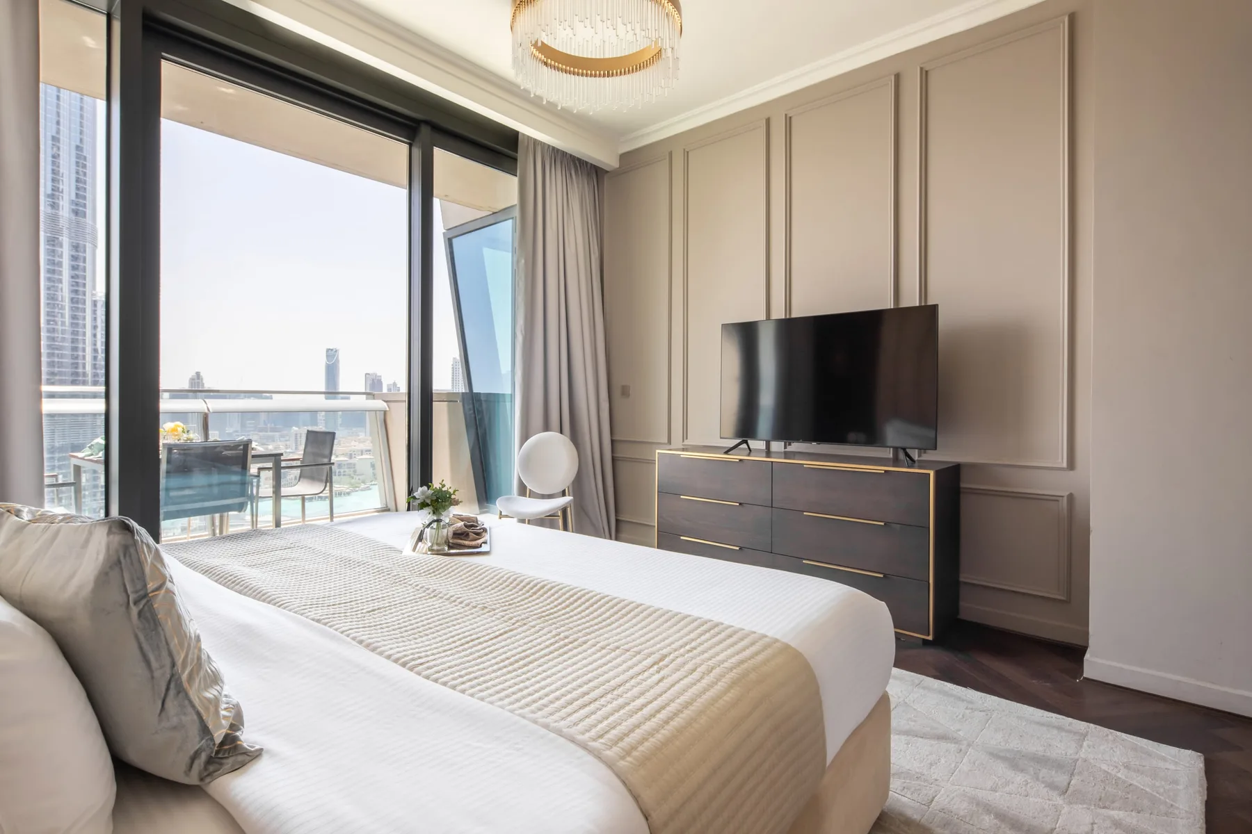 A bedroom with a bed, television, and glass doors opening onto a balcony.