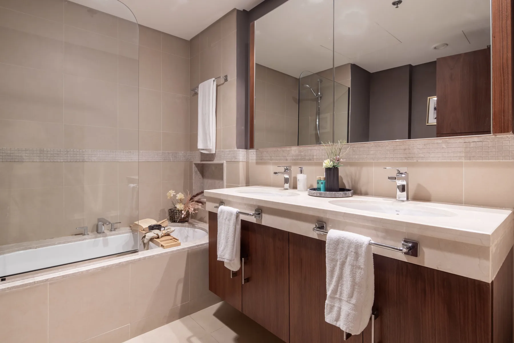 A bathroom with a bathtub and a wide vanity beneath a large mirror.