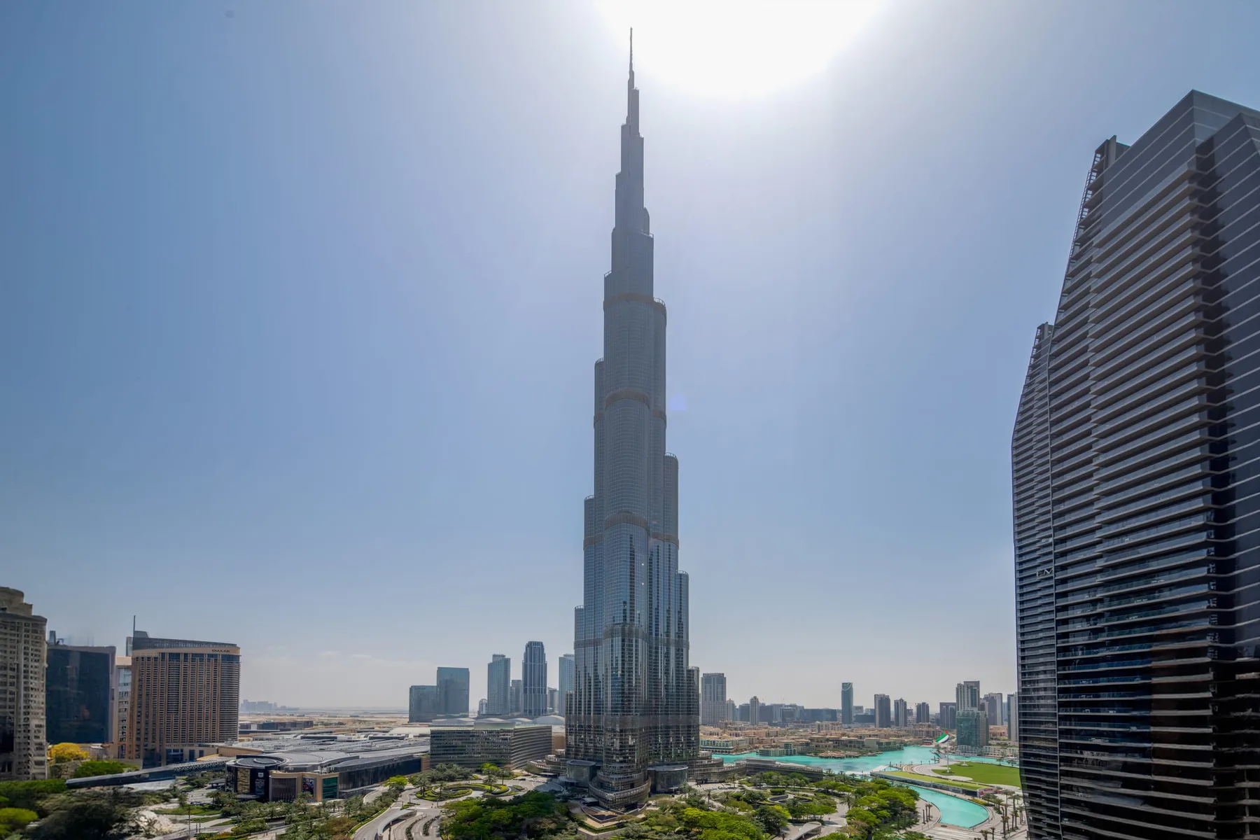 A city skyline features a very tall central skyscraper and a curving roadway.