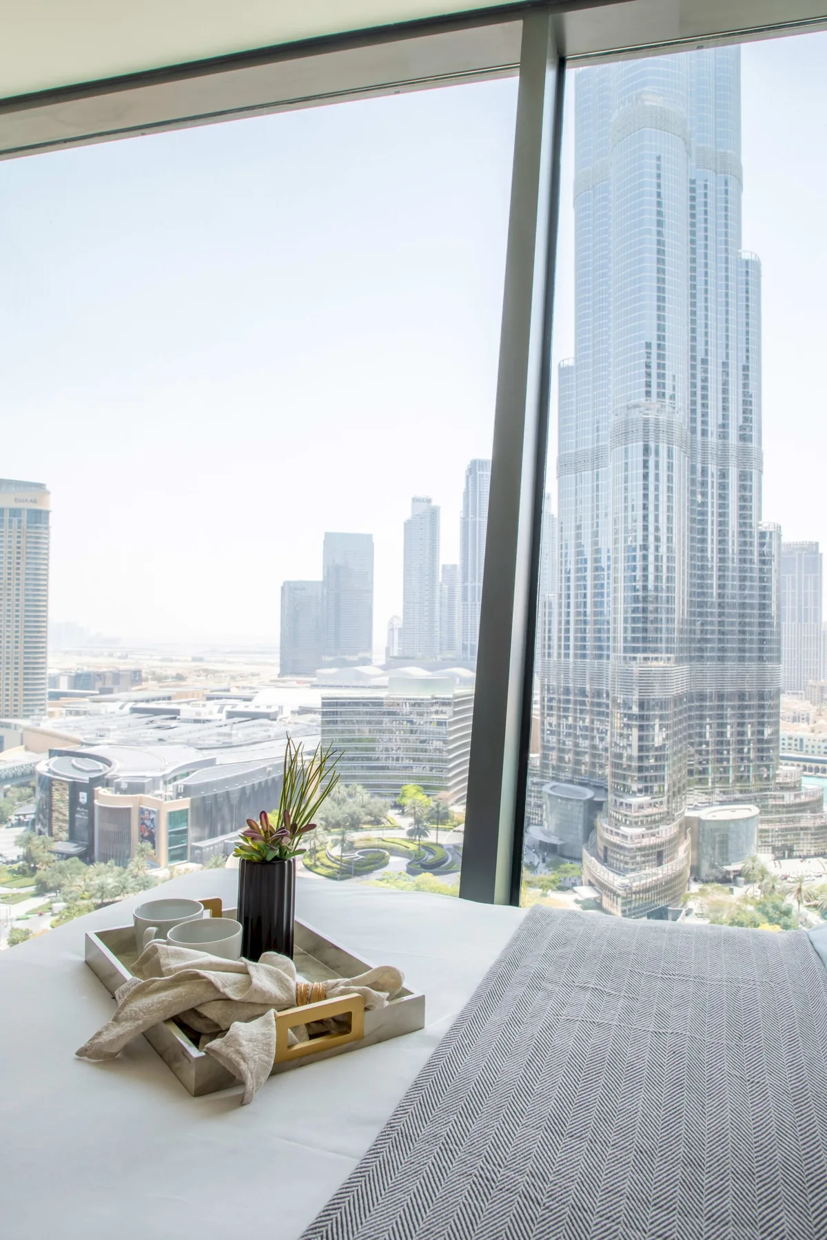 A bright room overlooks a city skyline through floor-to-ceiling windows.