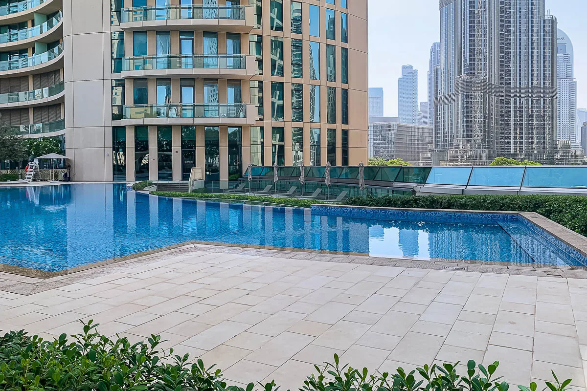 An outdoor swimming pool beside modern high-rise buildings.