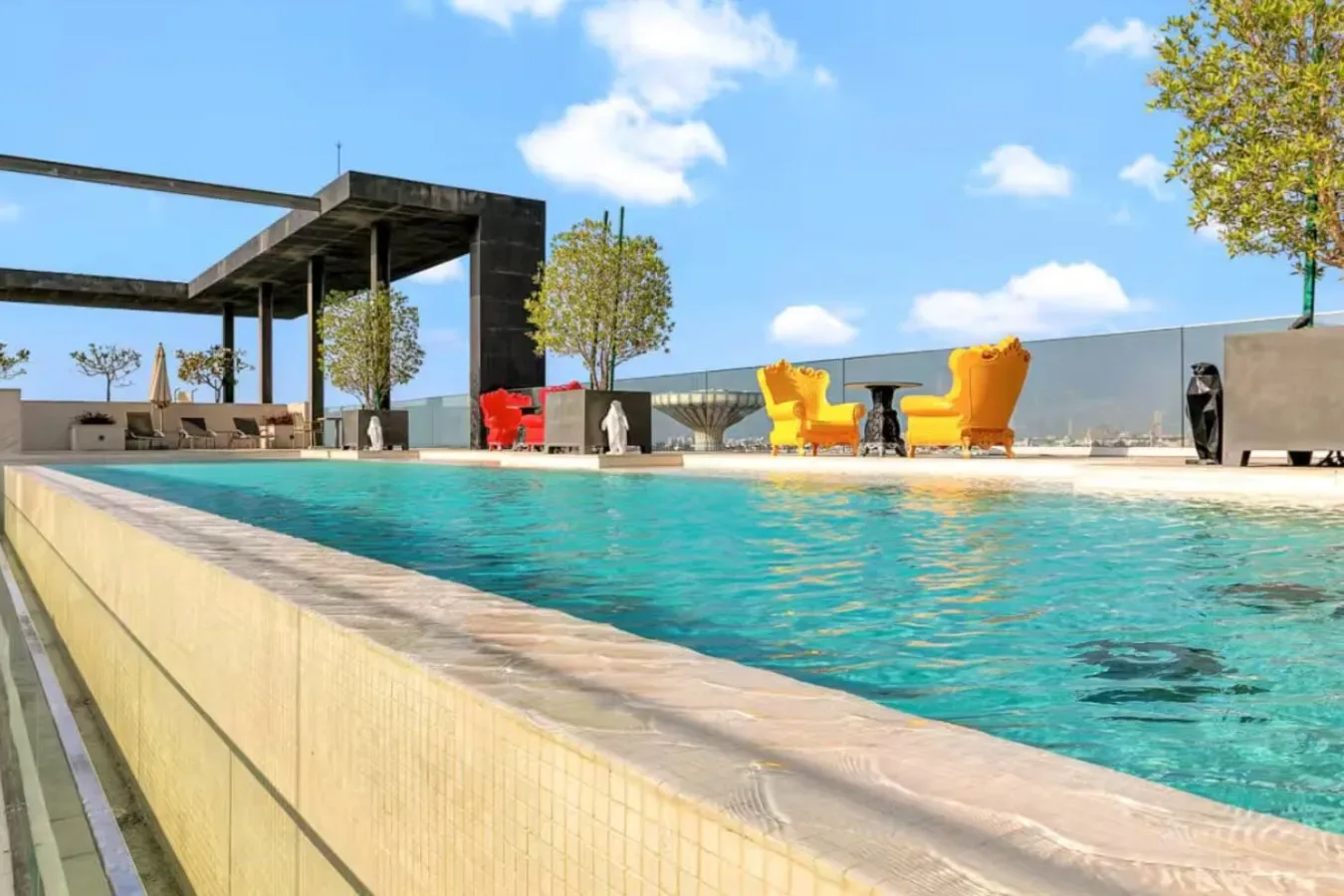 Una piscina al aire libre con asientos y árboles al fondo.
