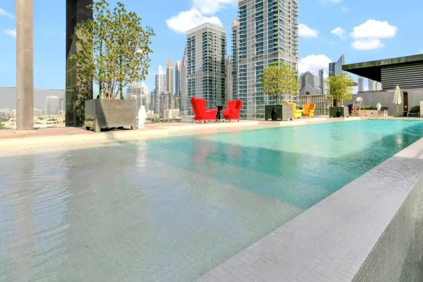 Una piscina en una azotea tiene vistas al perfil urbano, con asientos junto al borde.