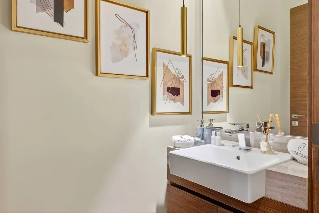 Un lavabo de baño está bajo cuadros enmarcados y luces colgantes.