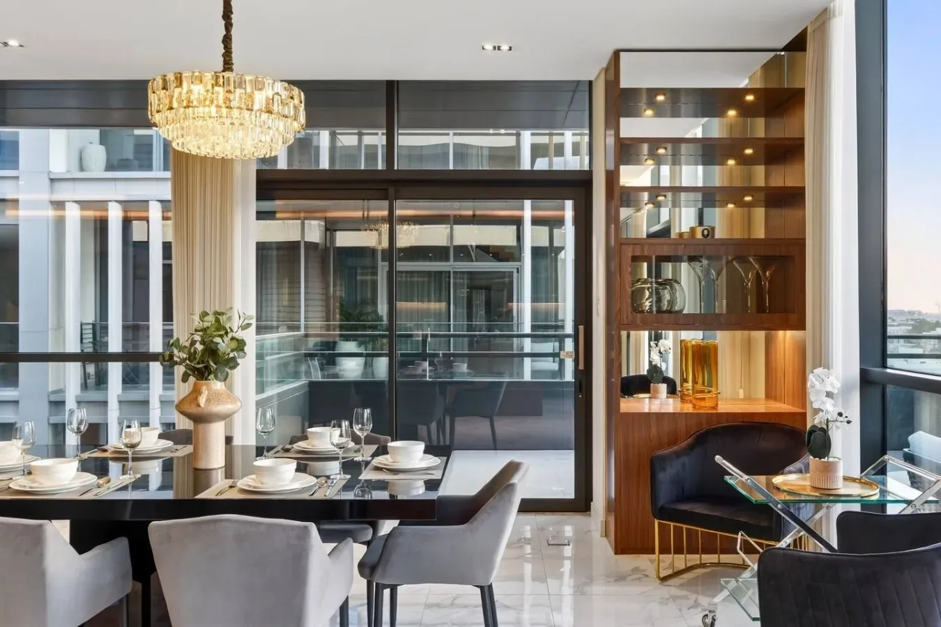 Un comedor con la mesa puesta junto a una estantería con puertas de vidrio.