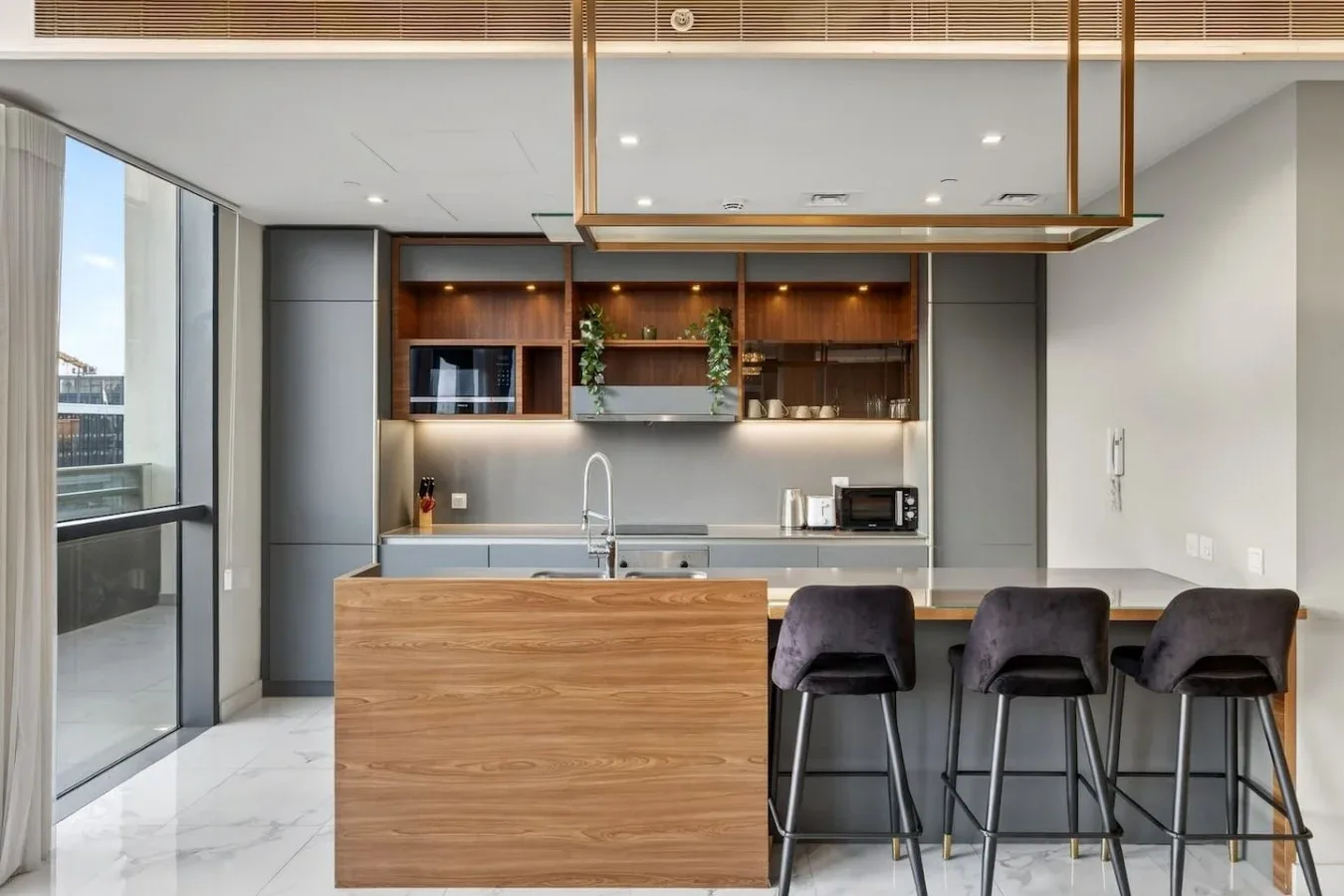 Una cocina moderna con una isla revestida de madera y asientos de barra.