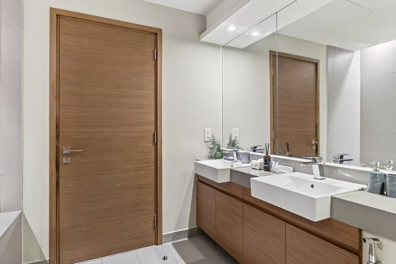 Un lavabo de baño con un espejo amplio y una puerta de madera.