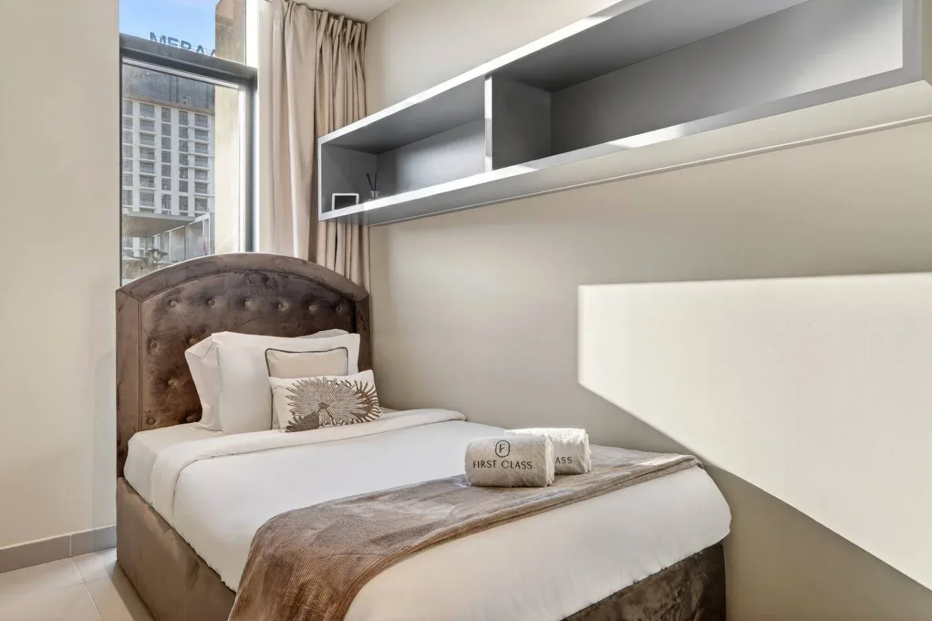 Un dormitorio con una cama bien tendida debajo de estantes empotrados.