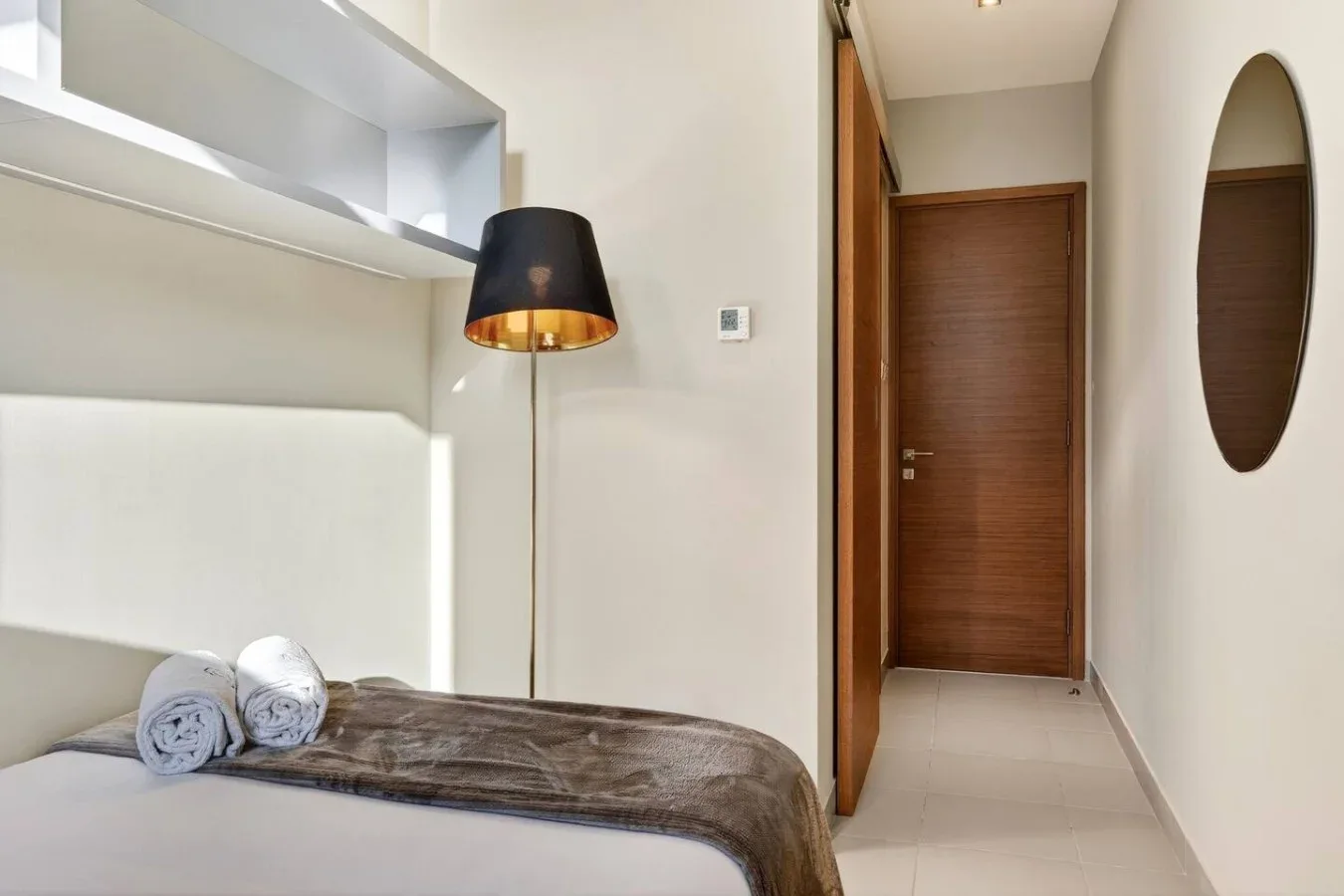 Un dormitorio con una cama bien arreglada y una puerta de madera al fondo.