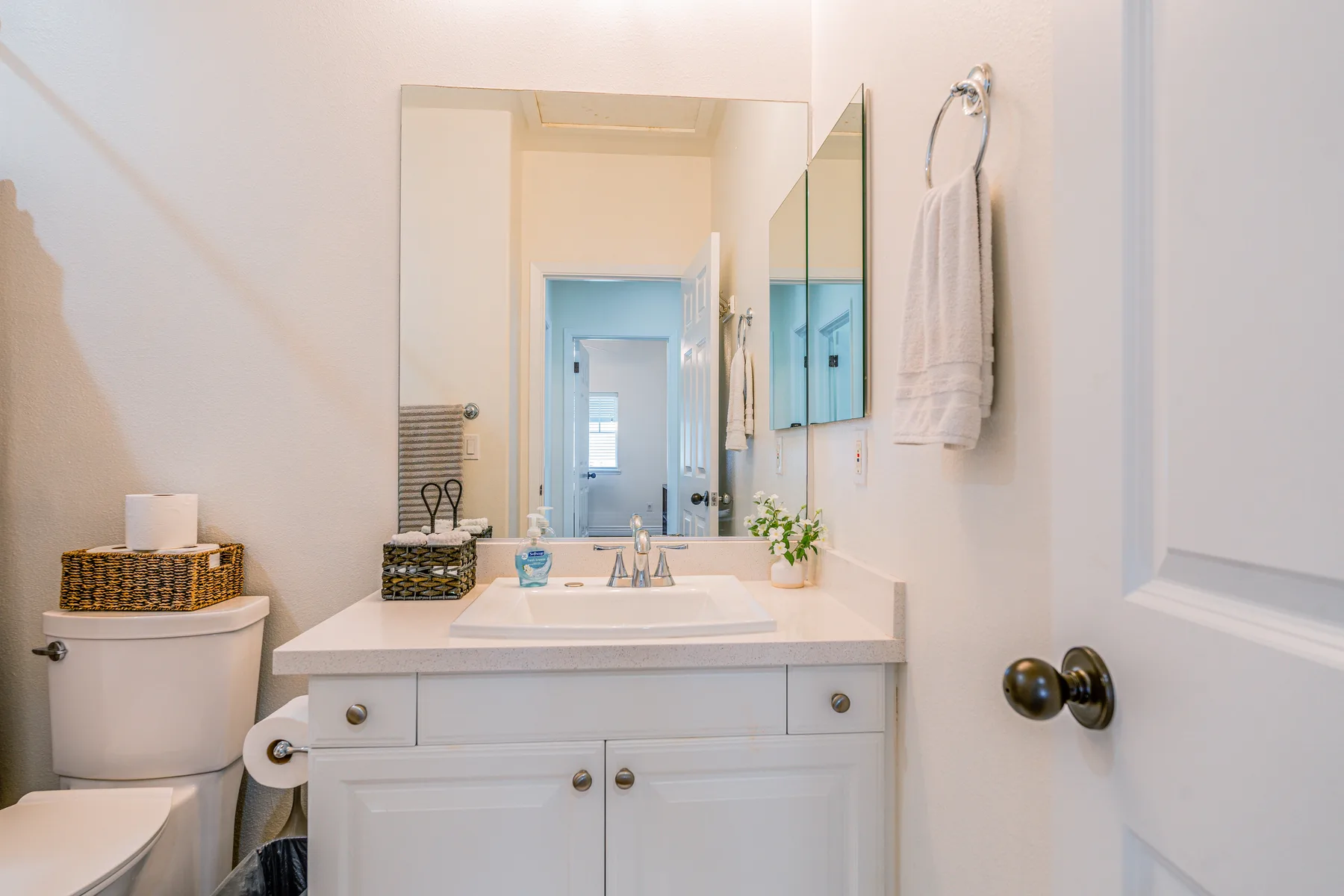 Un baño luminoso con lavabo, espejo y toalla blanca.