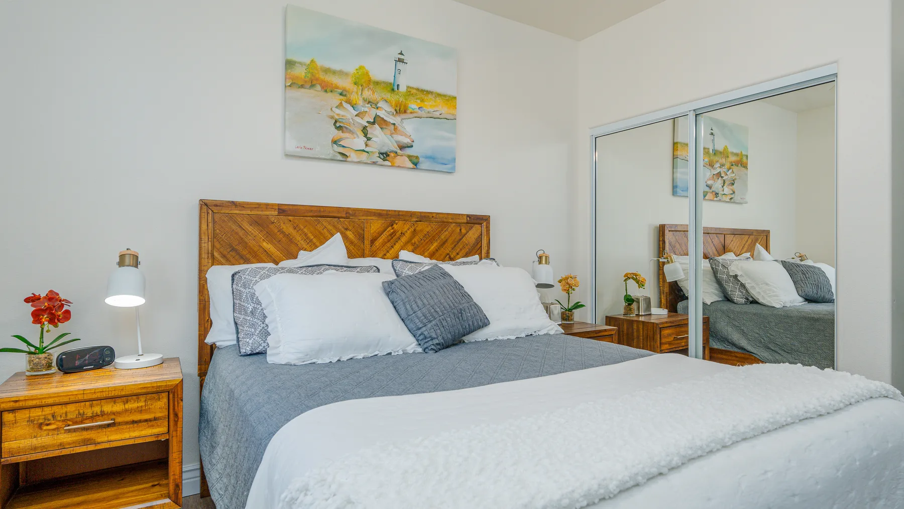 Un dormitorio con una cama bien tendida y un cuadro colorido sobre el cabecero.