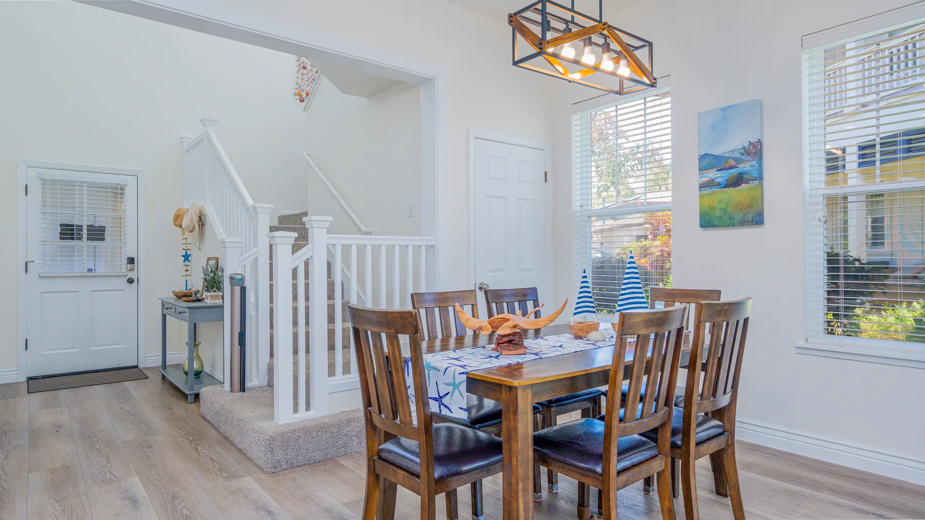 Comedor con una mesa de madera y sillas junto a una escalera.