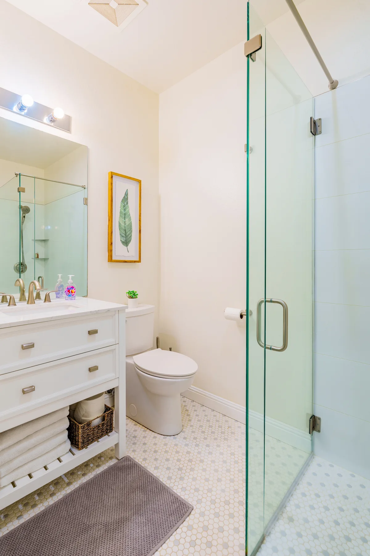 Un baño luminoso con lavabo, inodoro y ducha de vidrio.