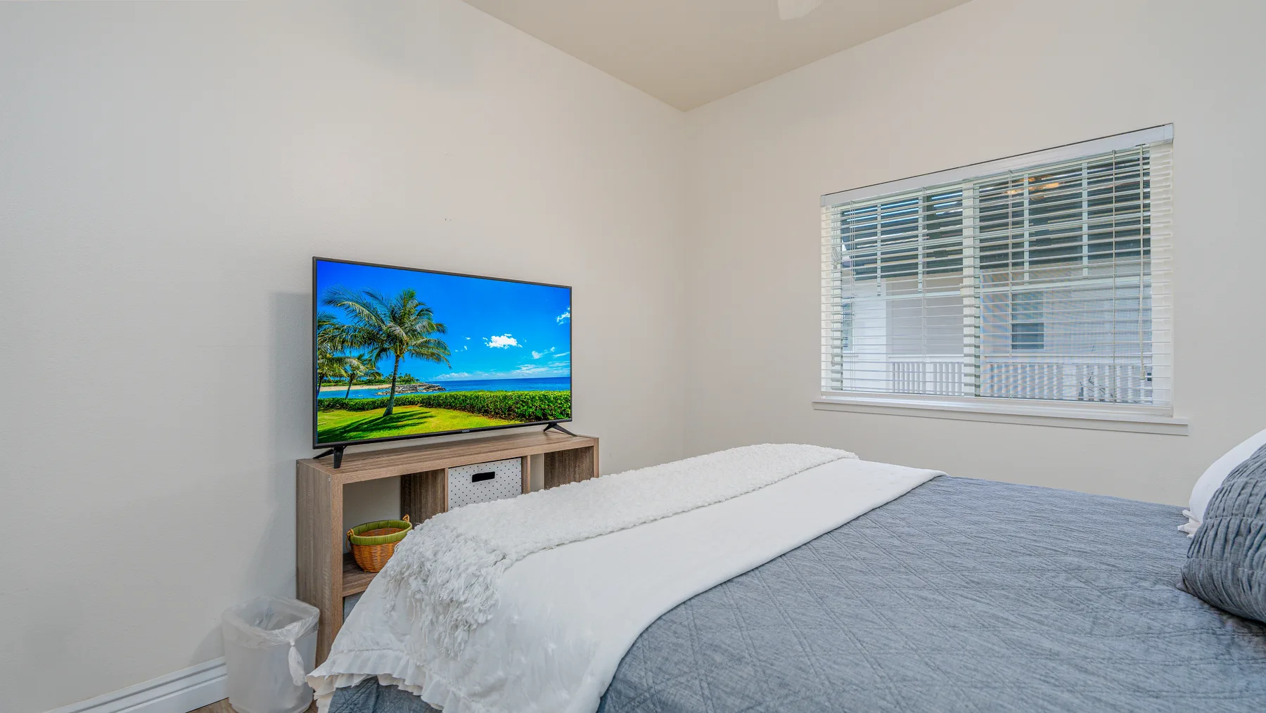Un dormitorio con una cama, un televisor y una ventana con persianas.