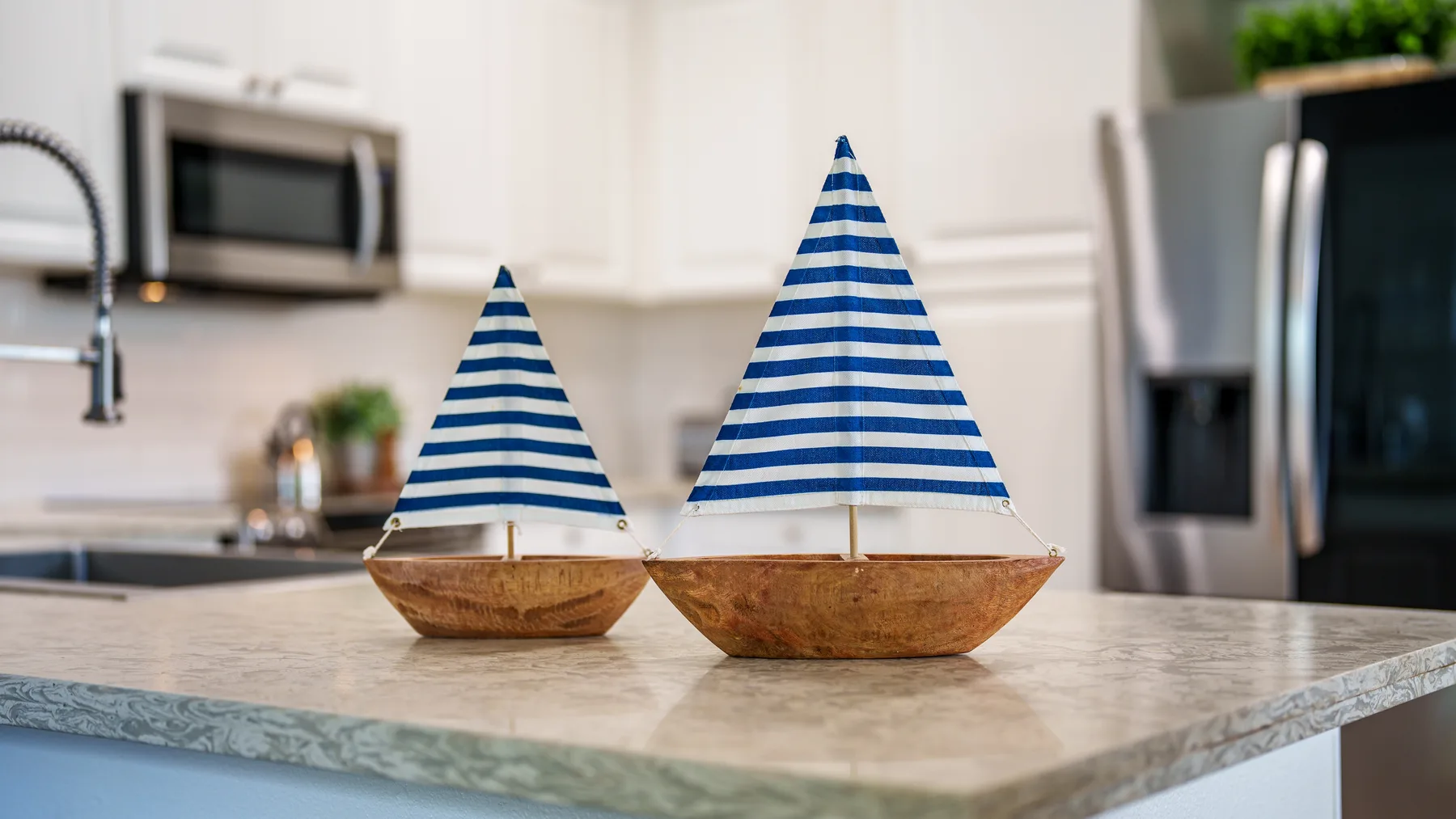 Una cocina luminosa con dos pequeños adornos de veleros sobre la encimera.