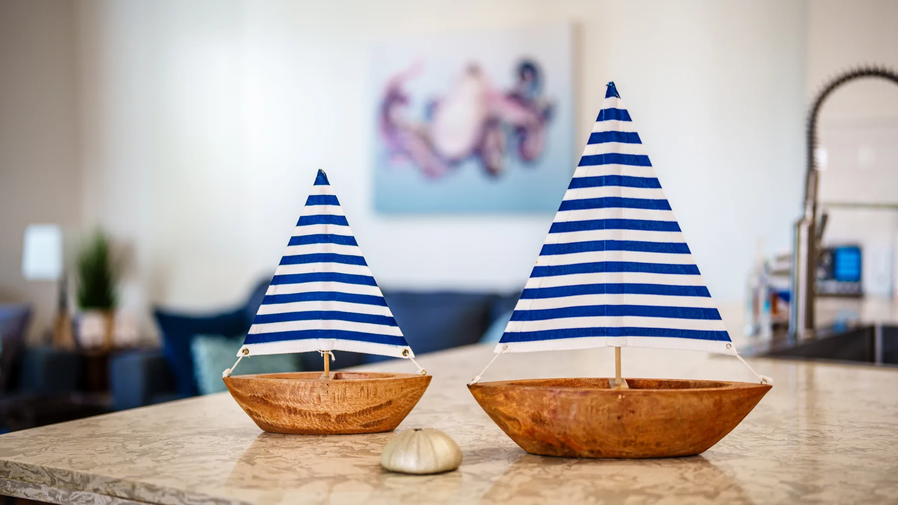 Dos barcos de vela en miniatura están sobre una encimera en una sala de estar.