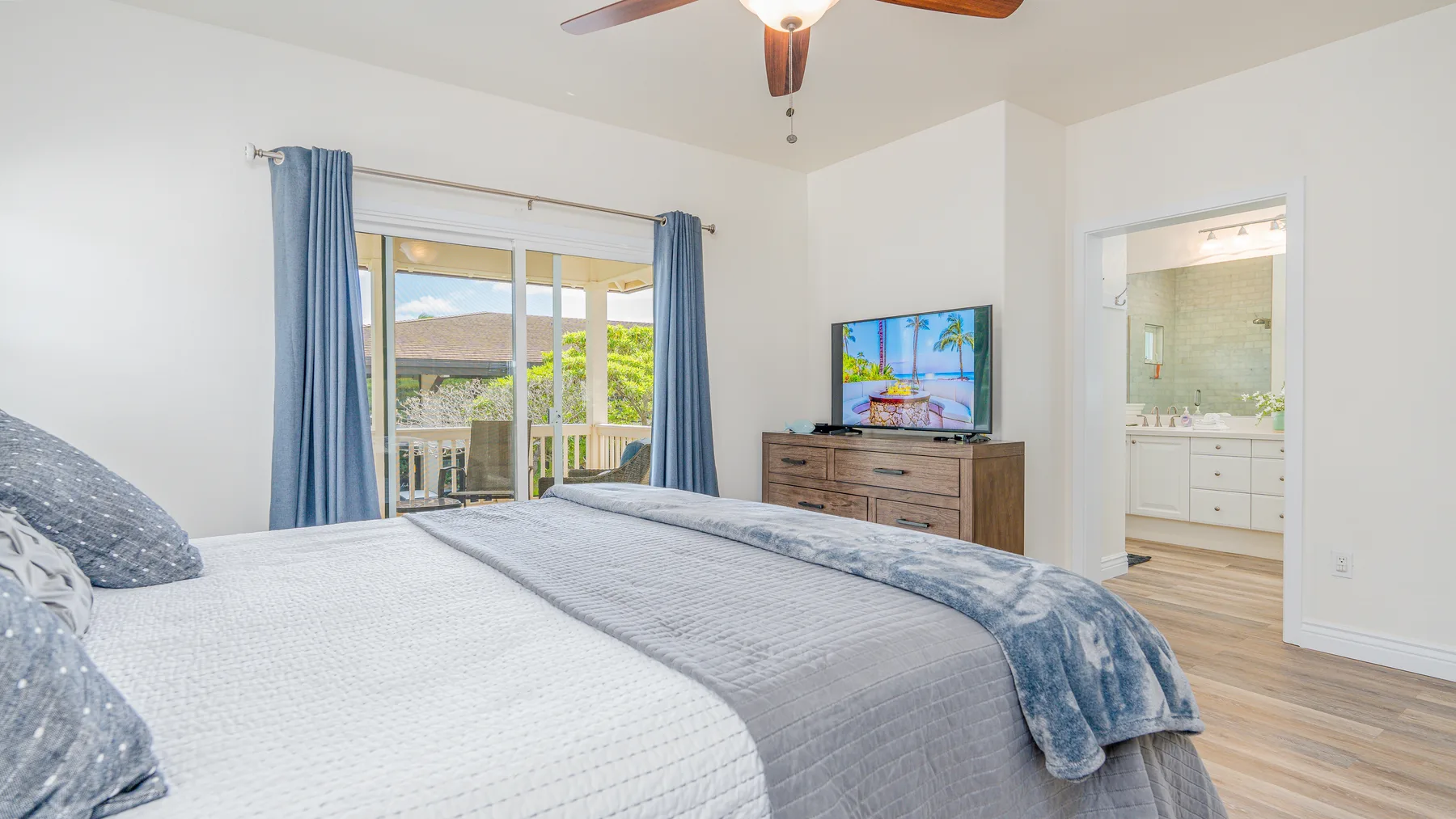 Un dormitorio luminoso con una cama, un televisor y puertas corredizas de vidrio.